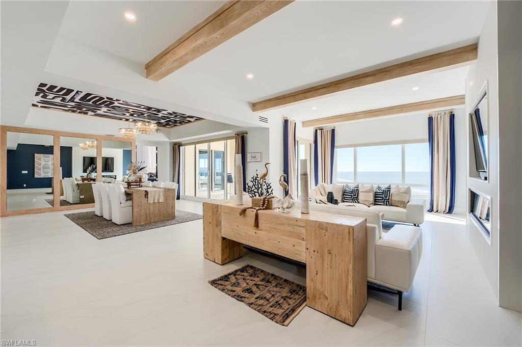 Open-plan living and dining room with wood ceiling beams and ocean views.