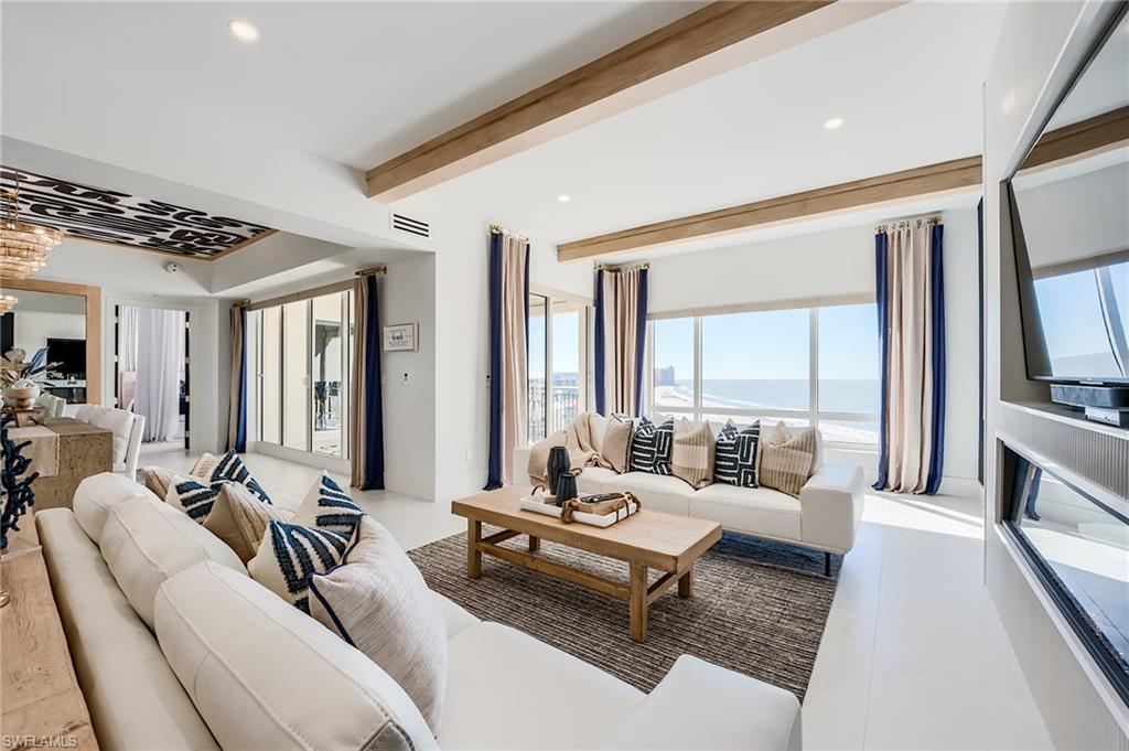 Living room with white sofas and ocean views through floor-to-ceiling windows.