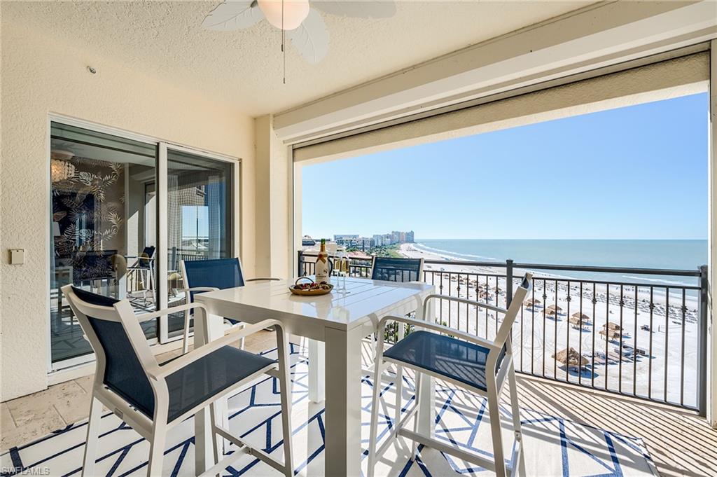 Condominium balcony with white dining set overlooking a sandy beach and the Gulf of Mexico.