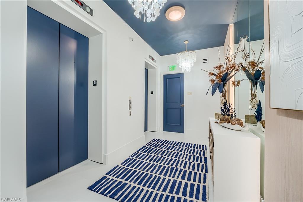 Elevator lobby with blue doors, chandeliers, and a blue-and-white patterned rug.