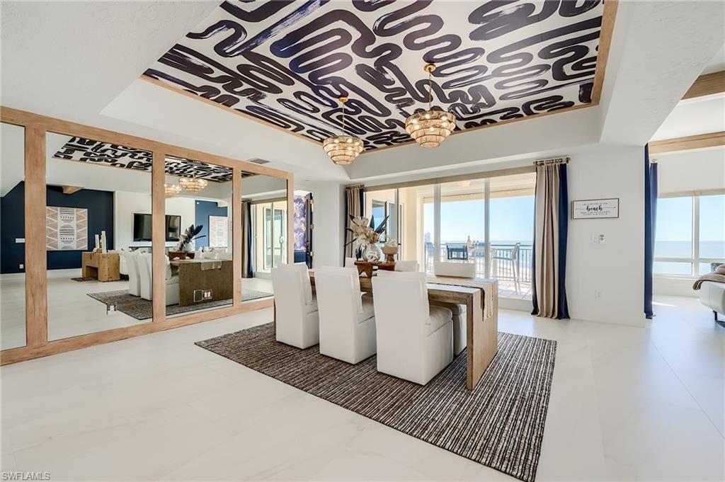Dining room with a patterned ceiling, mirrored wall, and balcony overlooking the water.