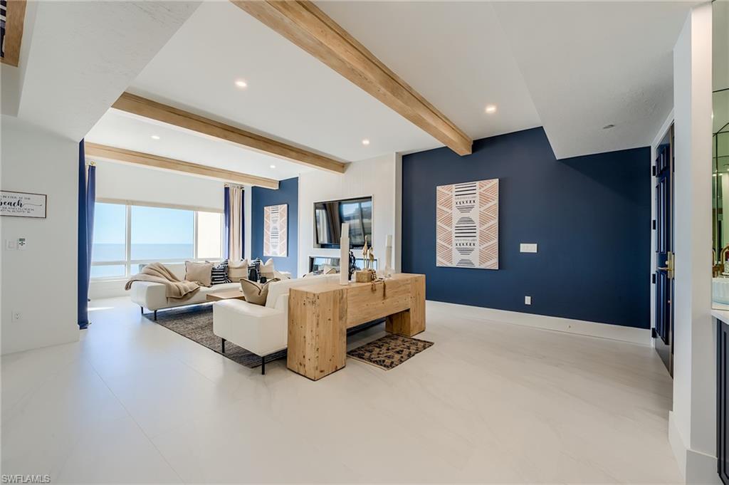 Condo living room with white sofas, exposed wood ceiling beams, and ocean views.