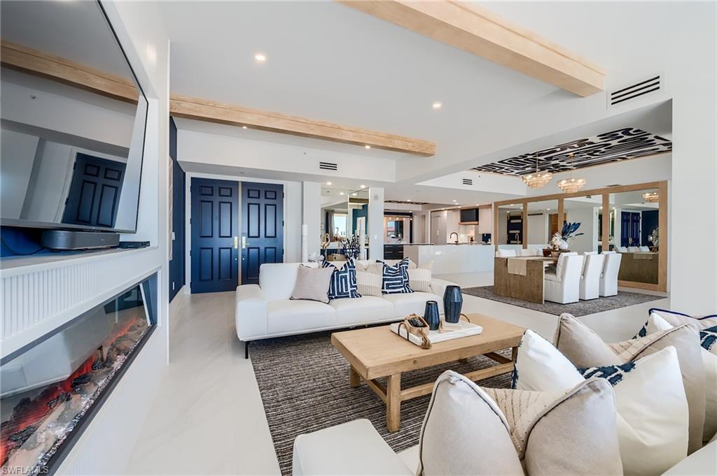 Living room with white sectional seating, a linear fireplace, and an open kitchen and dining area.