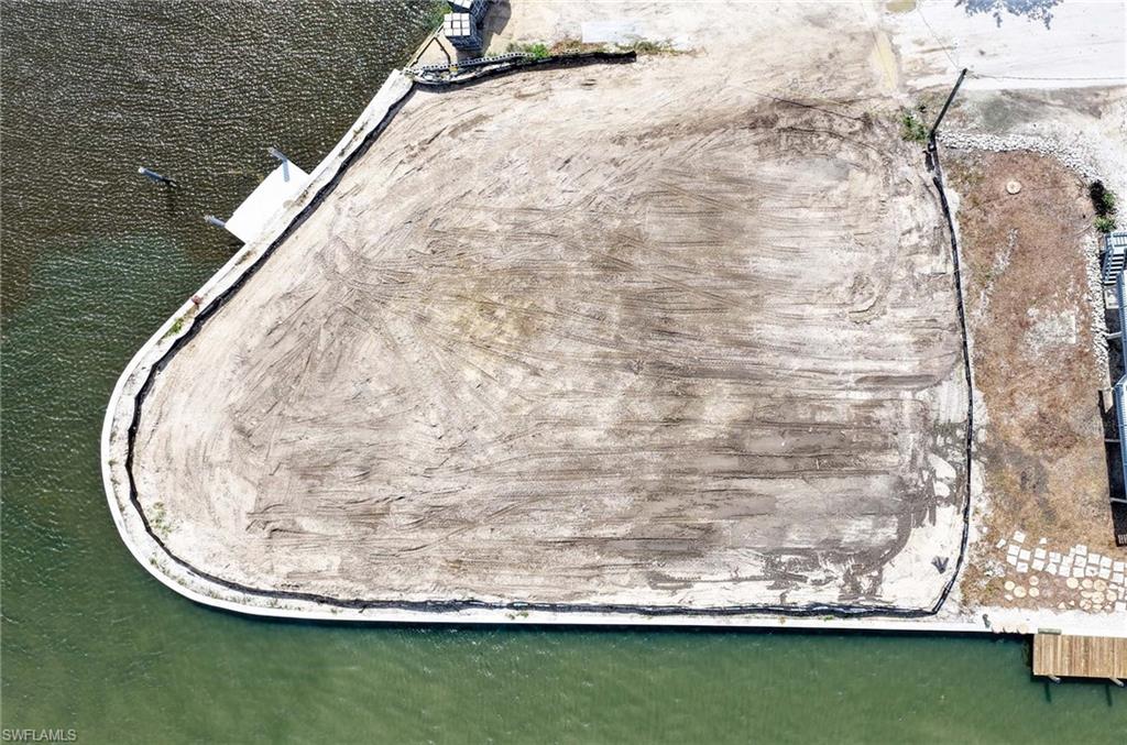 Cleared waterfront lot with a seawall and small dock beside the water.