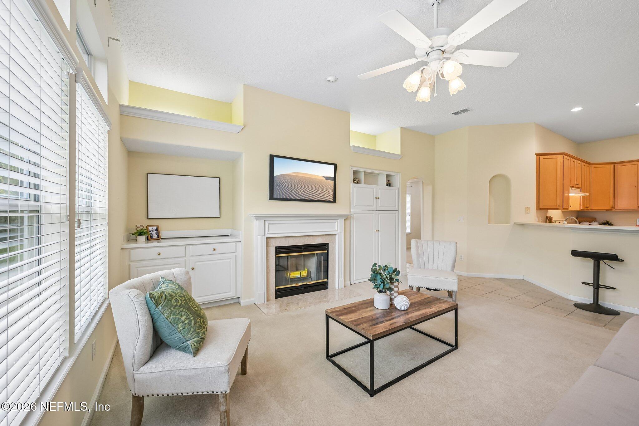 Living room with a fireplace, built-in cabinetry, and an open kitchen with wood cabinets.