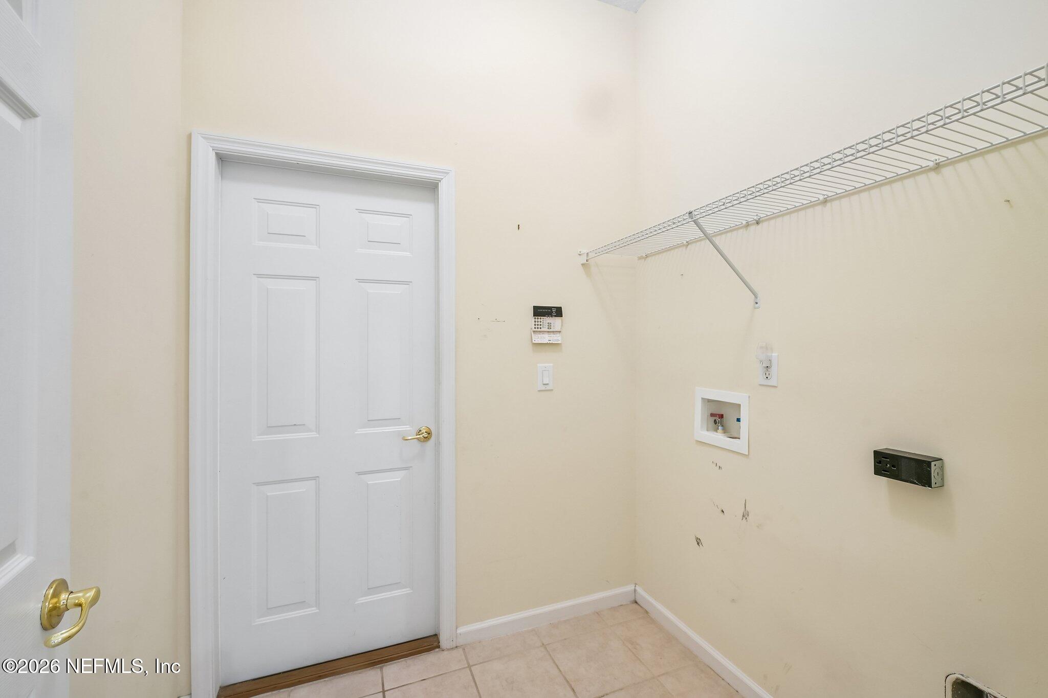 Vacant laundry room with wire shelving, laundry hookups, and a white paneled door.