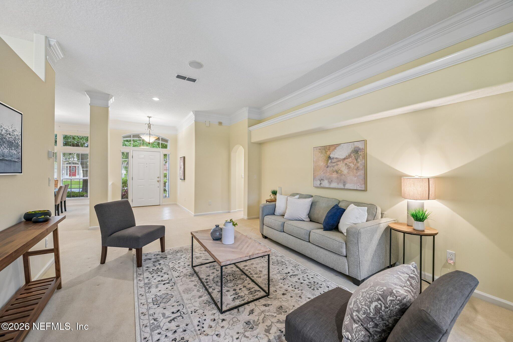 Furnished living room with a gray sofa, patterned rug, and bright front entry.