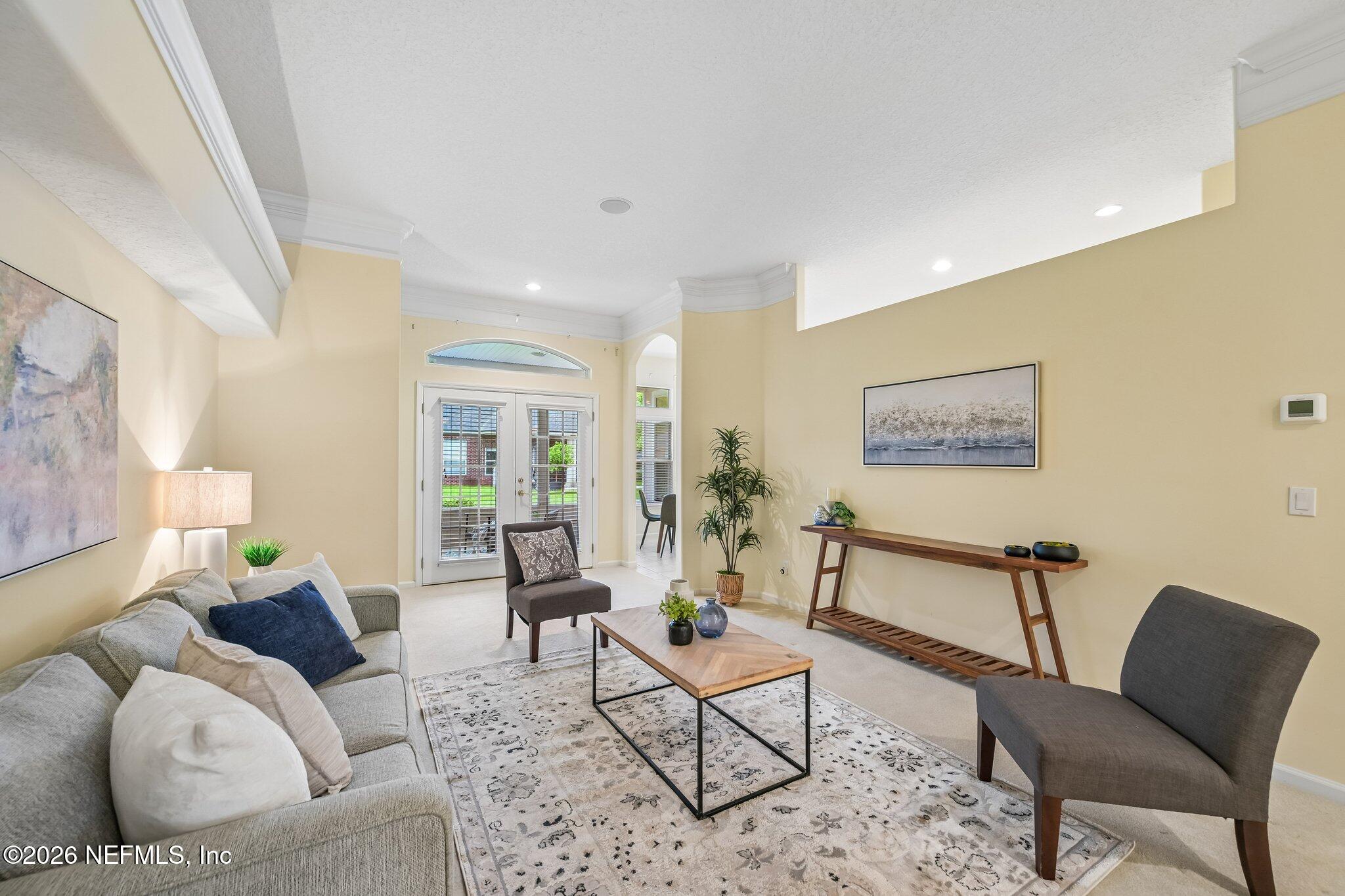 Furnished living room with French doors and a seating area around a wooden coffee table.