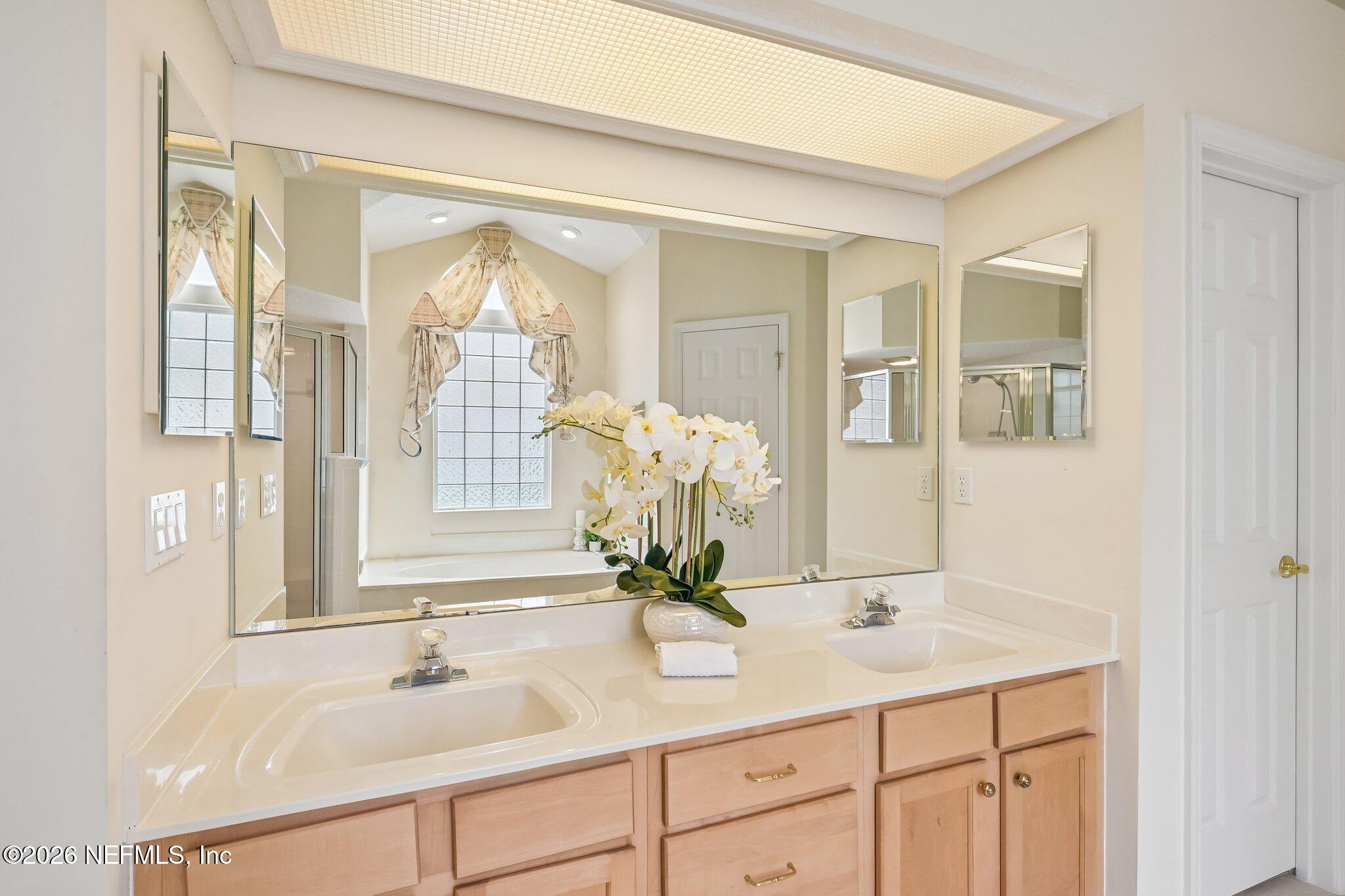 Bathroom with a double-sink vanity, large mirrors, and white orchids on the counter.