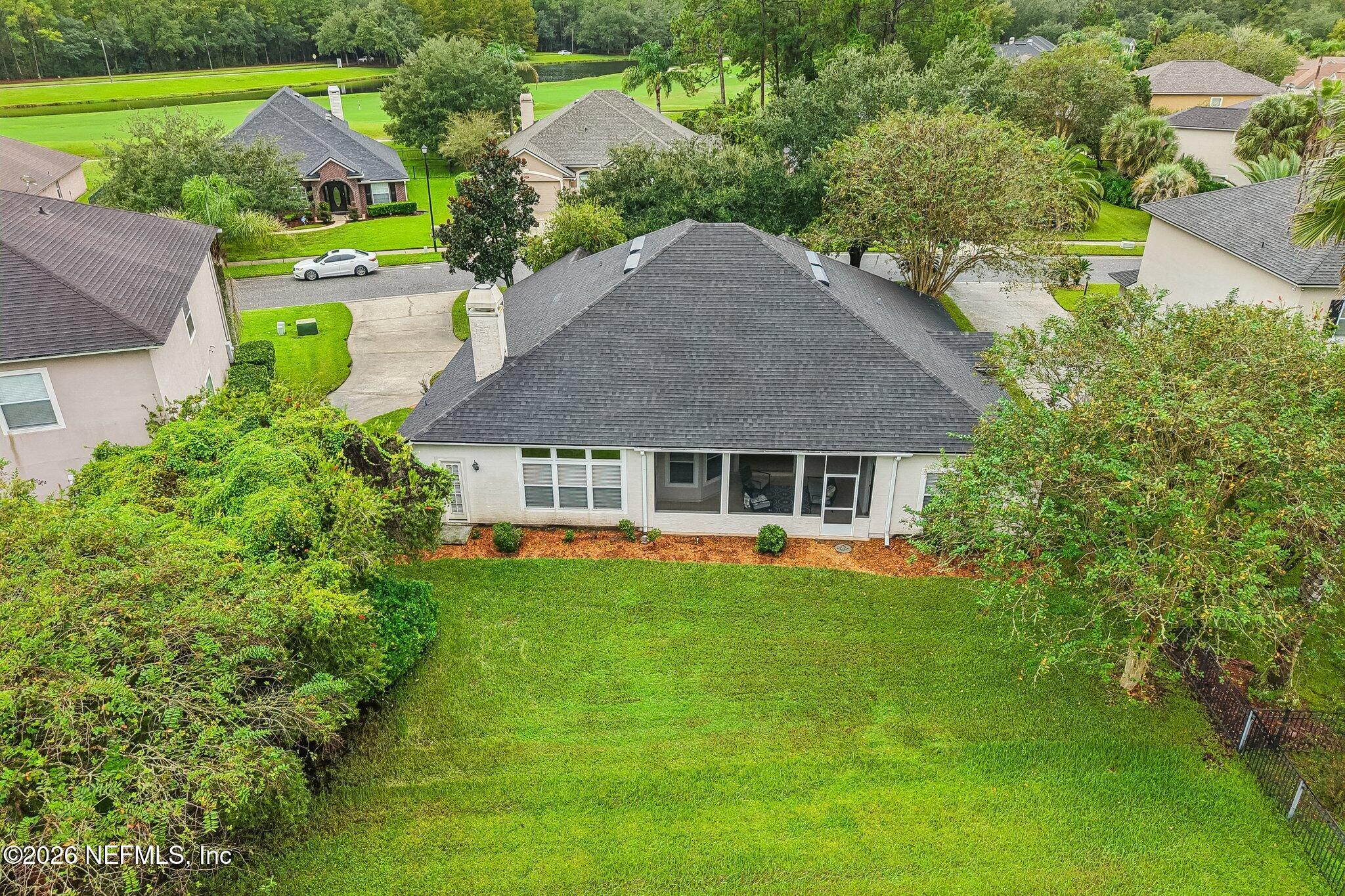 Aerial rear view of a home with a screened patio and spacious fenced lawn.