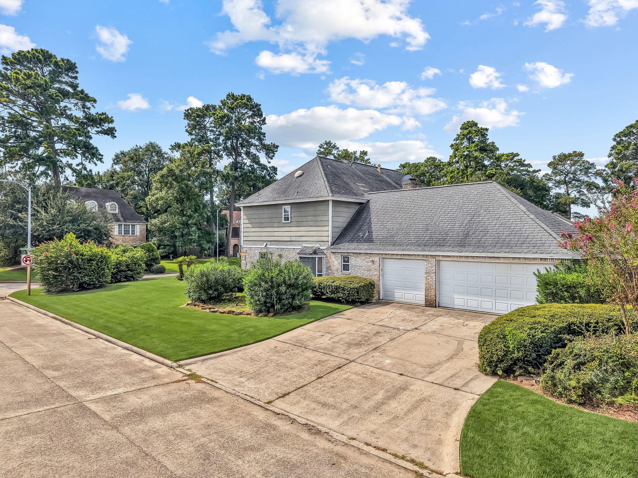House with stone facade and two-car garage on a landscaped corner lot.