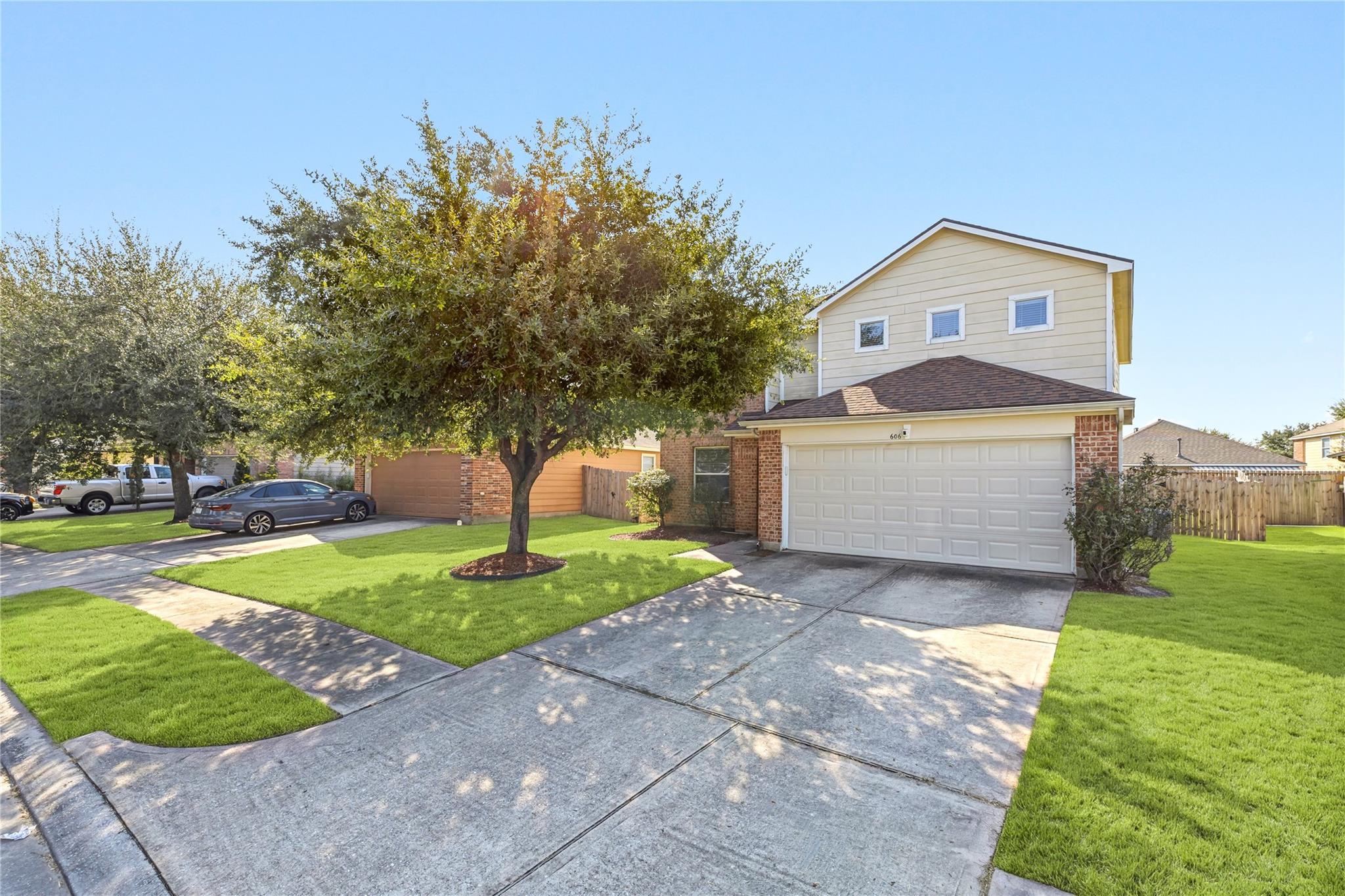 Two-story home with a double garage, mature shade tree, and broad front lawn.