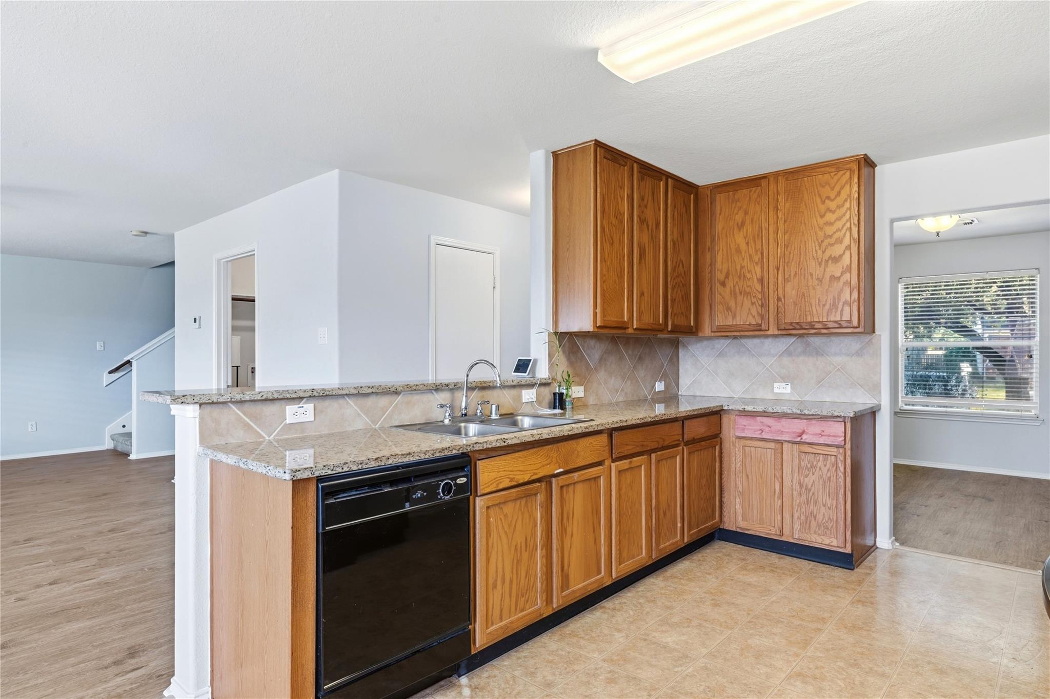 Kitchen with wood cabinets, speckled countertops, tiled backsplash, and a breakfast bar.