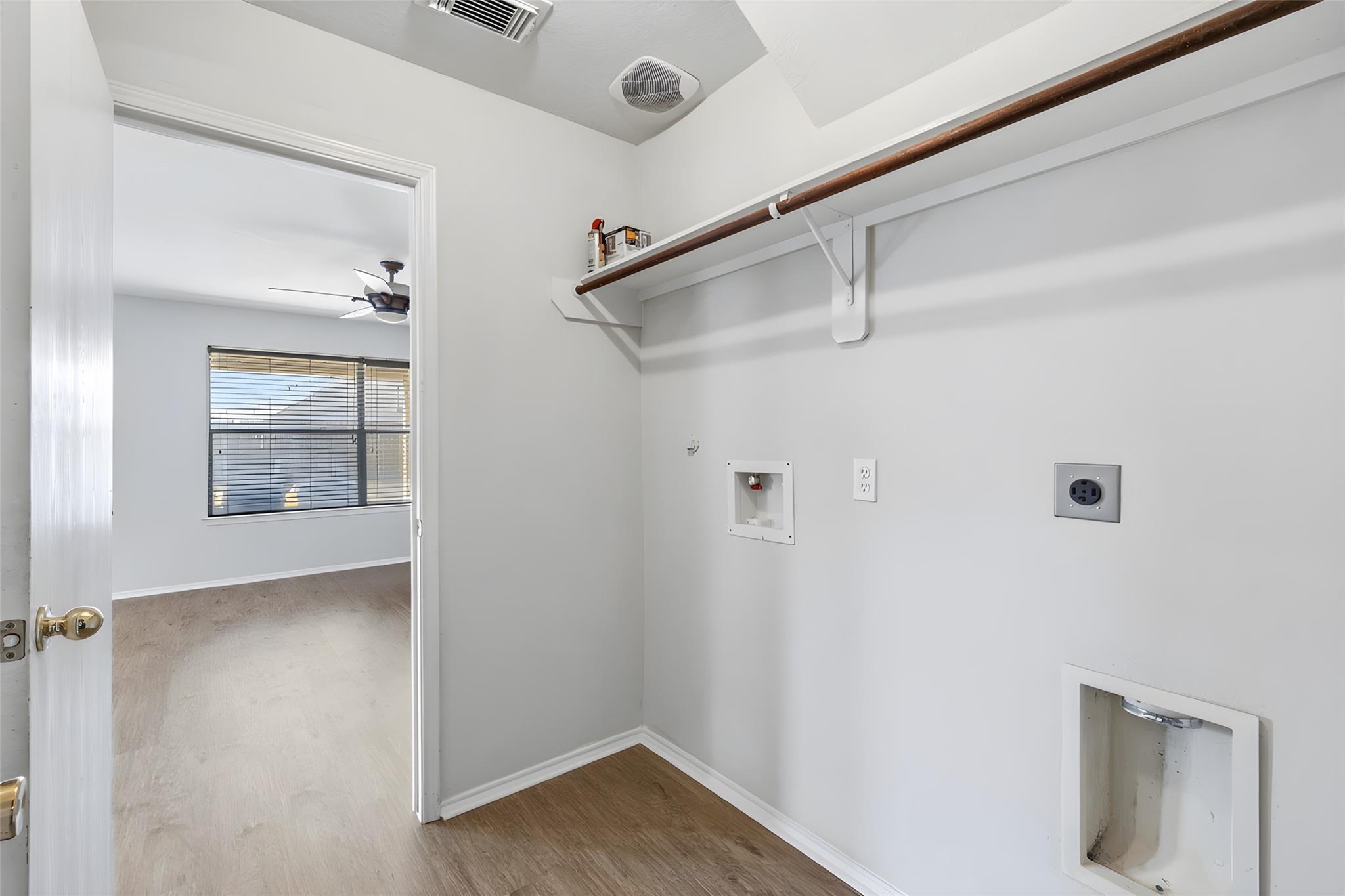 Laundry room with a hanging rod, washer and dryer hookups, and an open doorway.