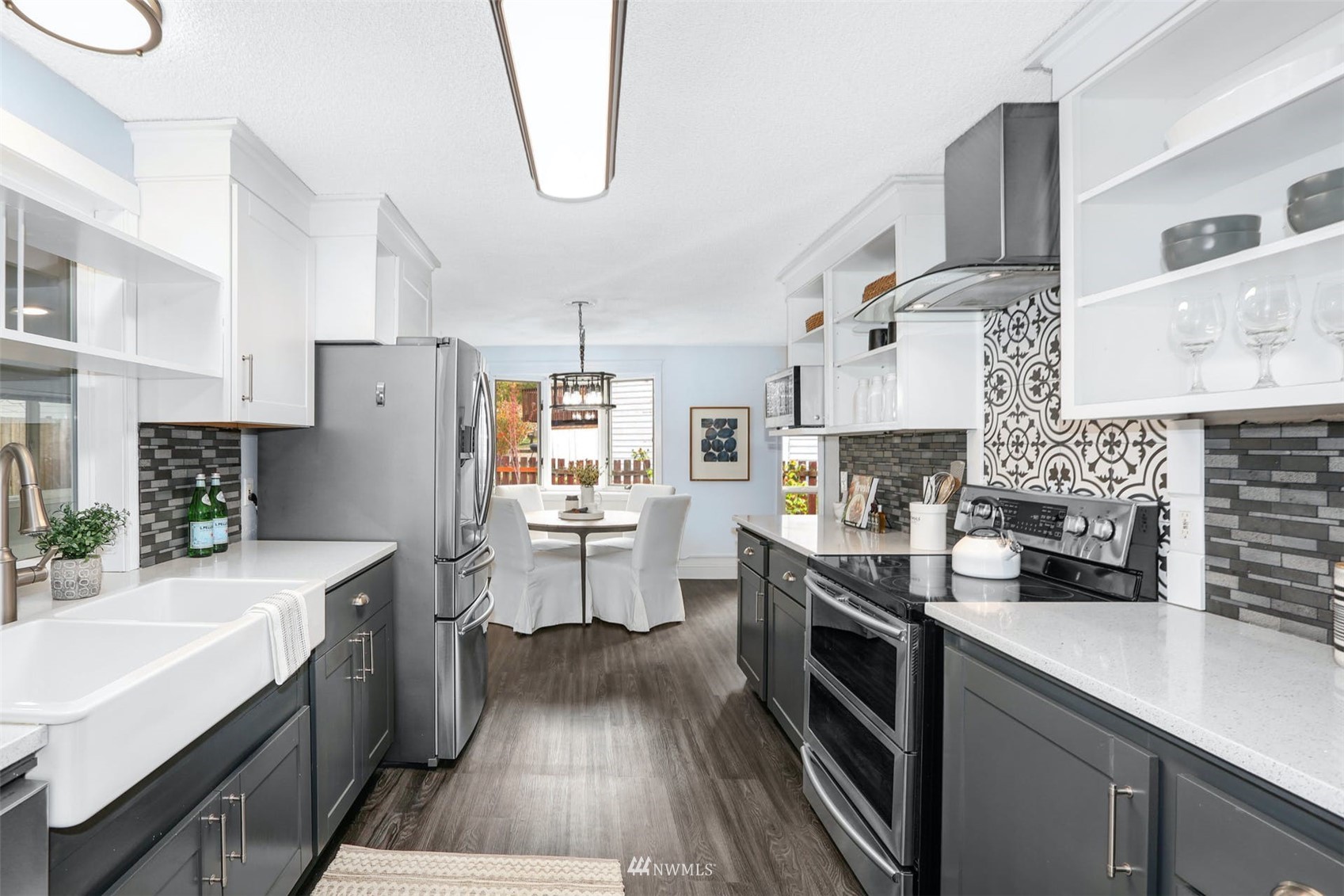 Remodeled kitchen with a farmhouse sink, stainless steel appliances, patterned backsplash, and adjoining dining area.