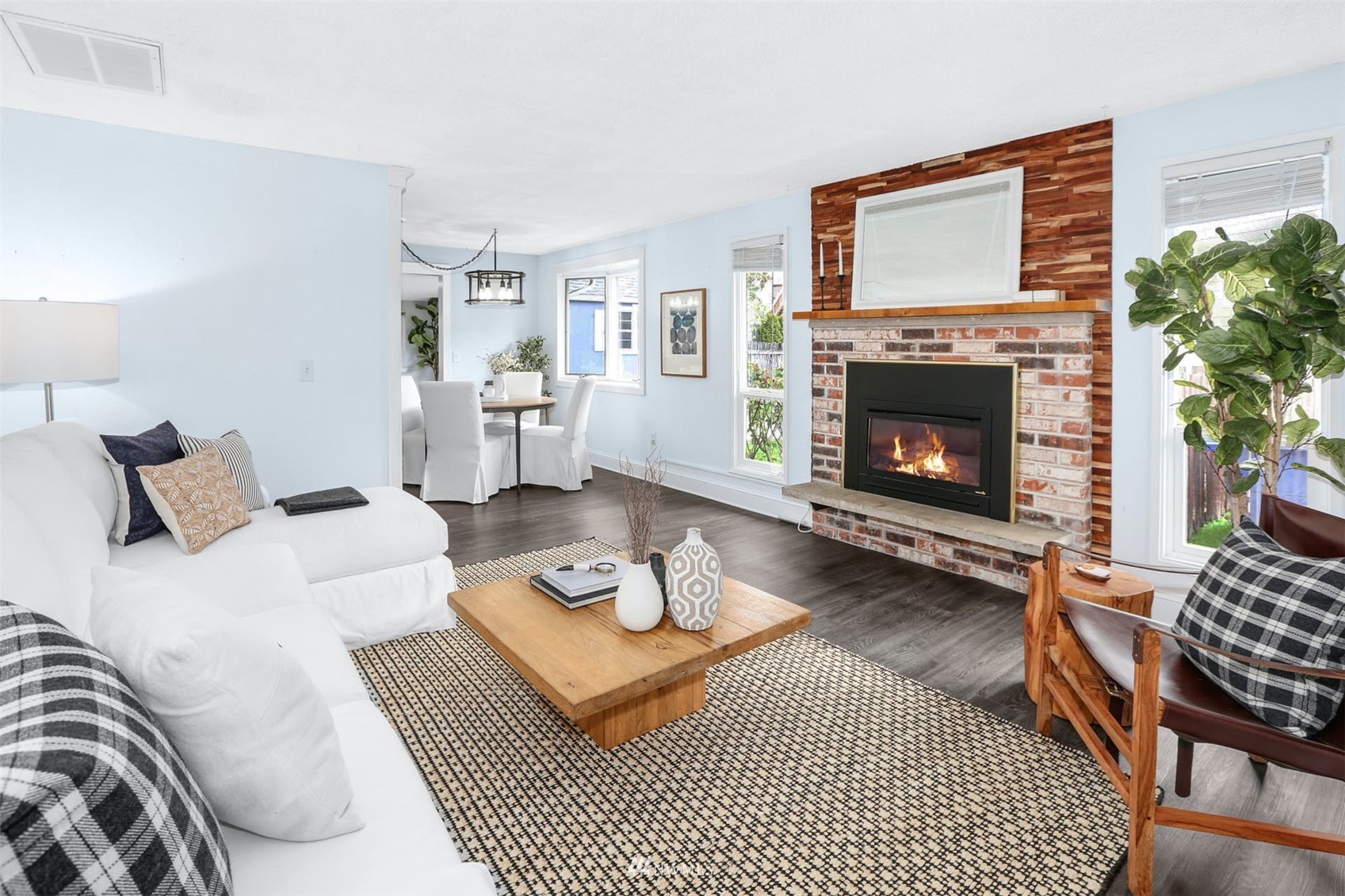 Living room with a white sectional and lit fireplace against a brick and wood accent wall.