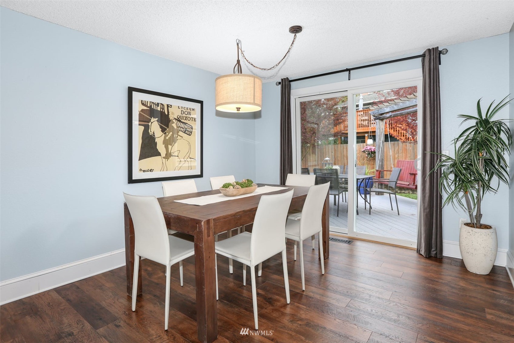 Dining room with a dark wood table, white chairs, and sliding glass doors to a patio.