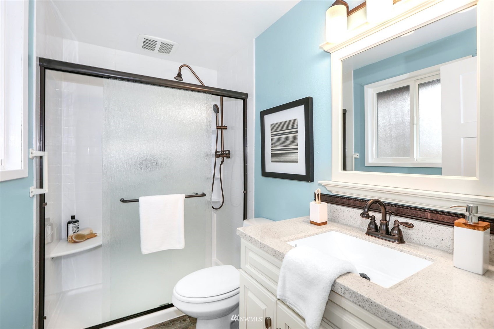 Bathroom with a glass-enclosed shower, turquoise walls, and a white vanity.