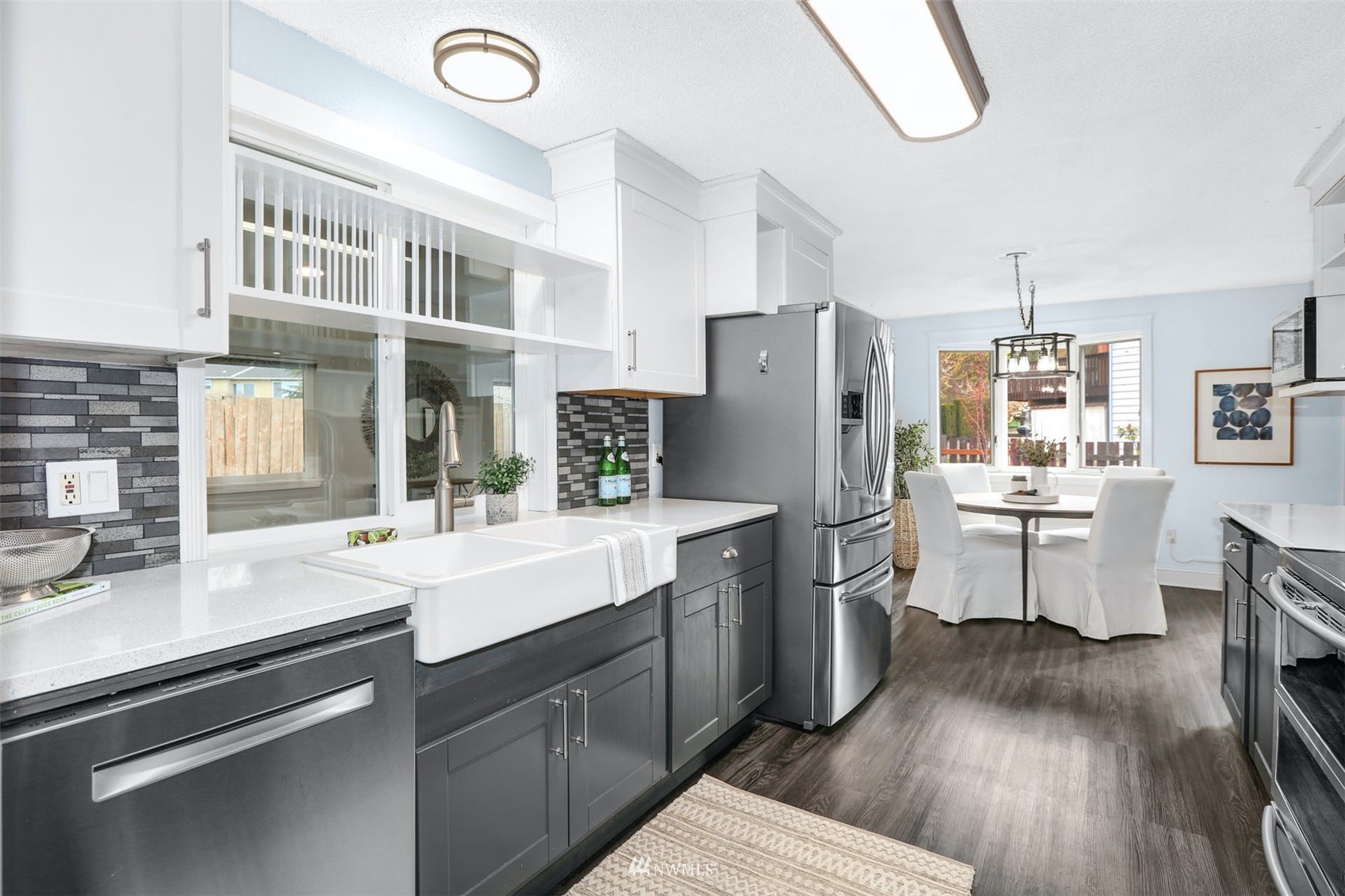 Updated kitchen with a farmhouse sink, dark gray cabinets, stainless appliances, and an adjoining dining nook.