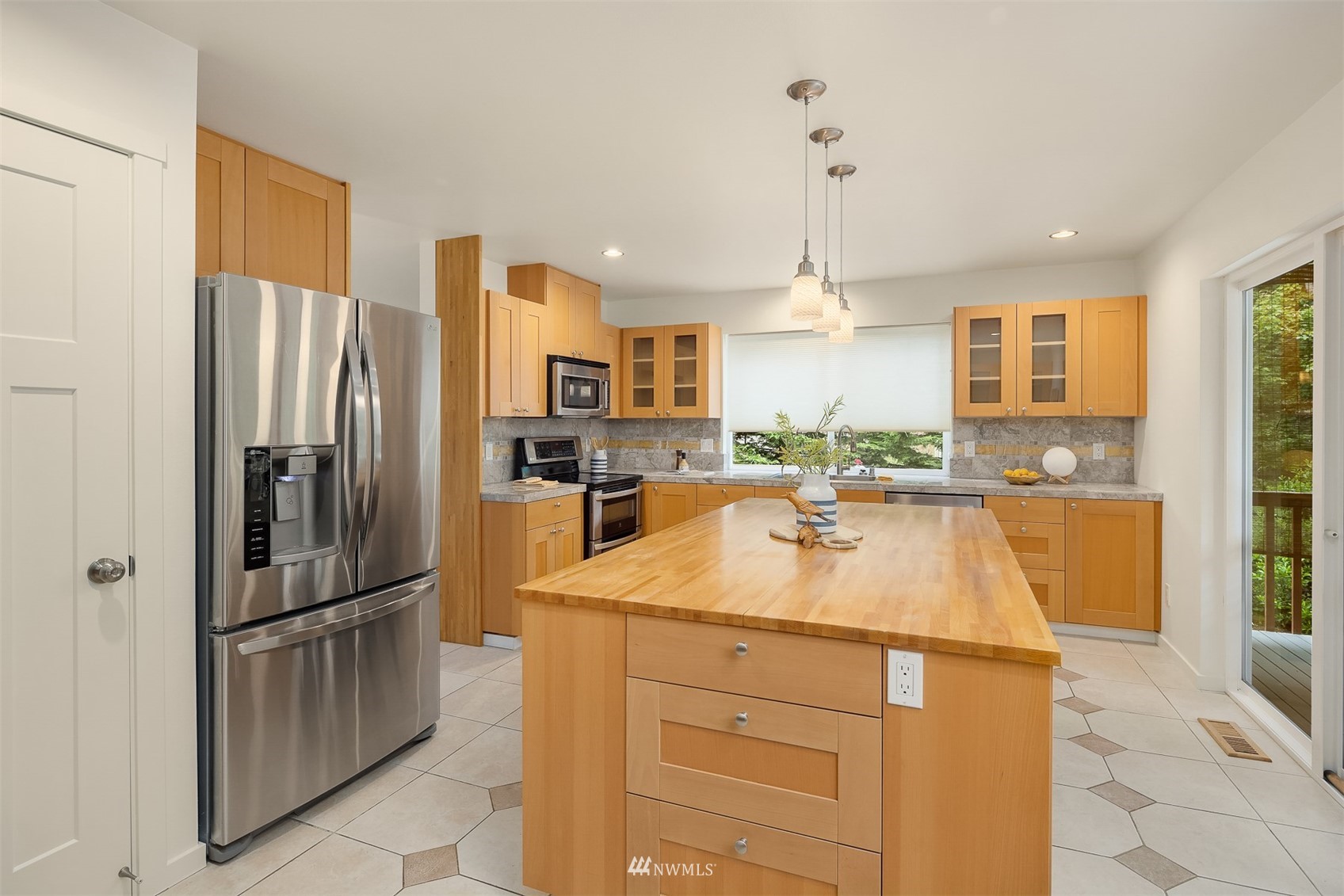 Kitchen with a large butcher-block island, honey-toned cabinets, and stainless steel appliances.