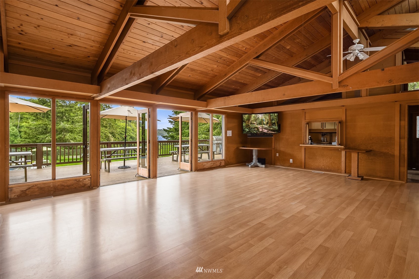 Unfurnished living room with a vaulted wood ceiling, exposed beams, and glass doors opening onto a deck.
