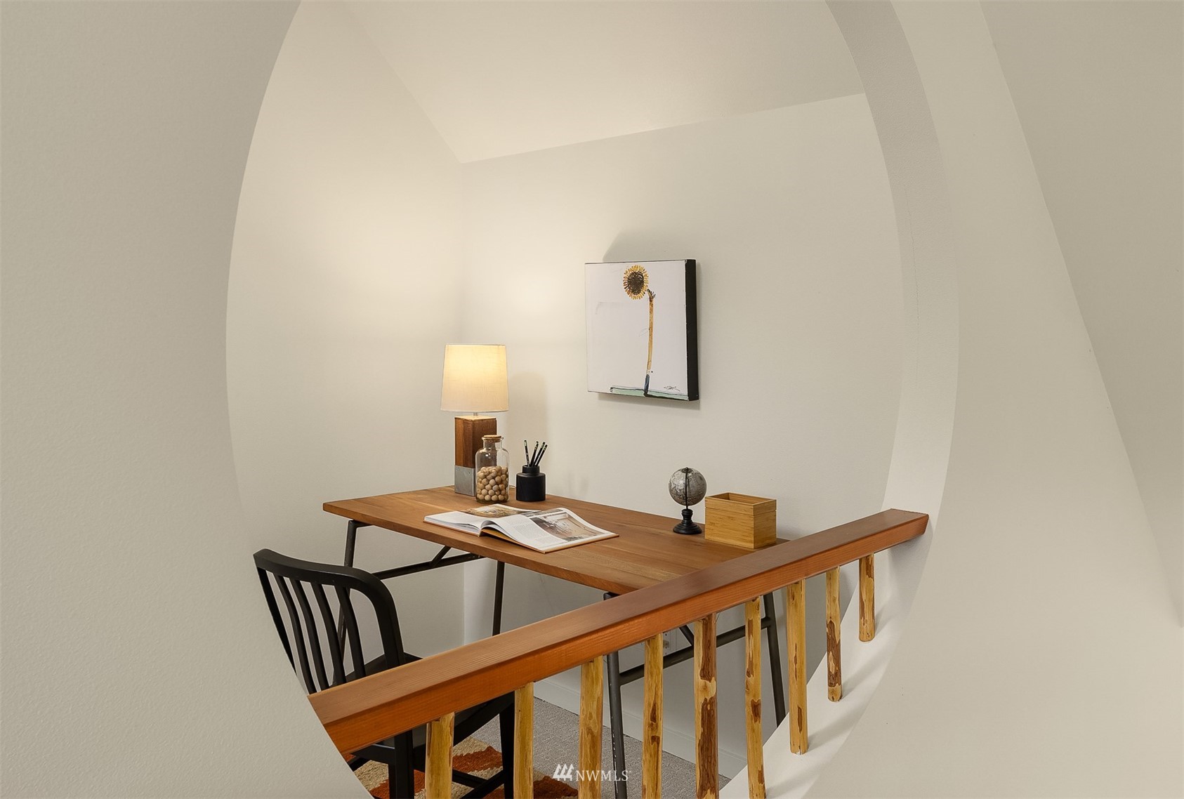 A furnished desk nook beneath an arched alcove, with a wooden desk and railing.