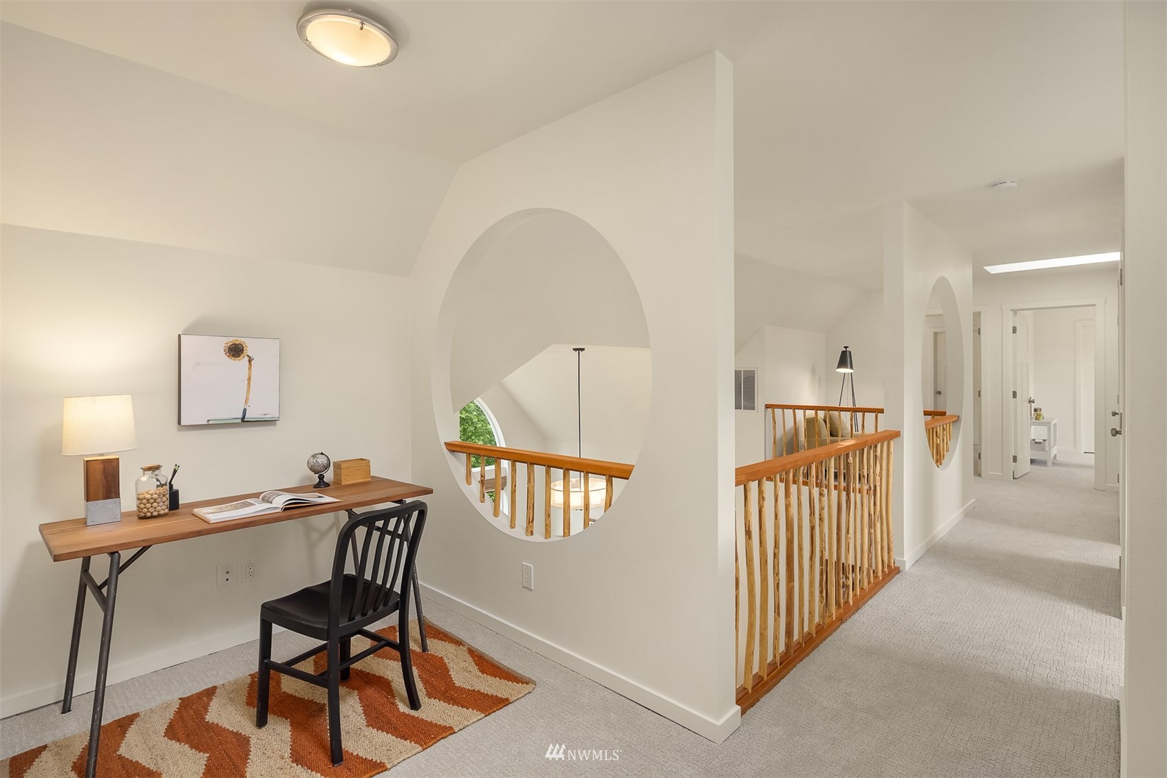 Upstairs landing with a desk nook, circular wall opening, and wood stair railings.