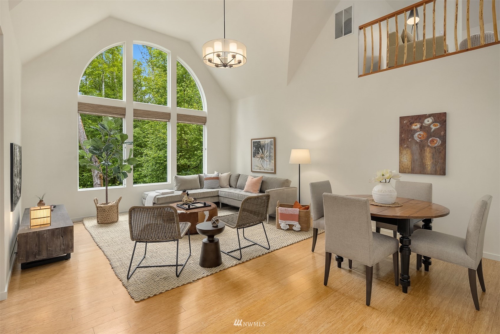 Living and dining room with vaulted ceiling, arched windows, and an open loft railing.