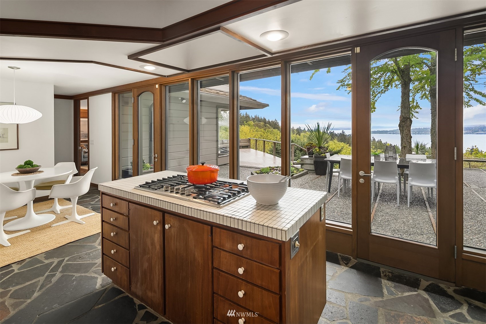 Kitchen with a tiled island and gas cooktop, opening to a patio overlooking the water.