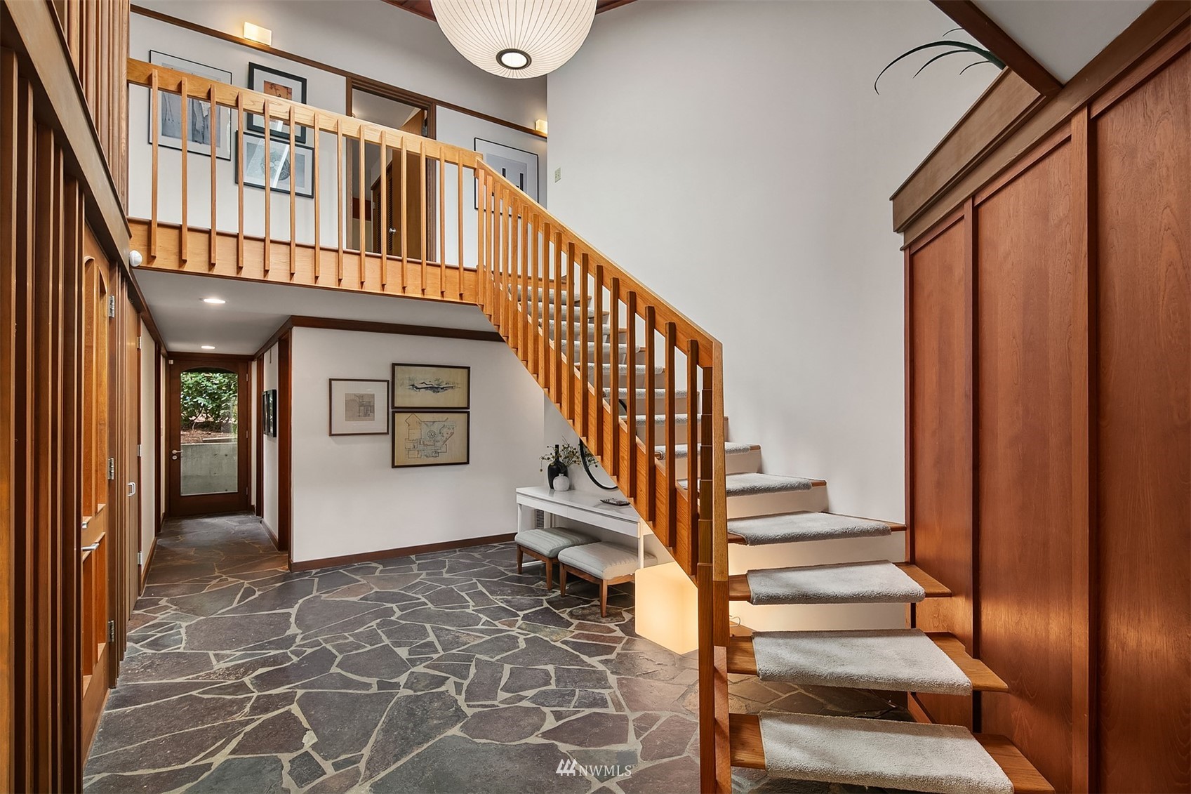 Entry hall with a wood staircase, stone tile floor, and framed artwork.