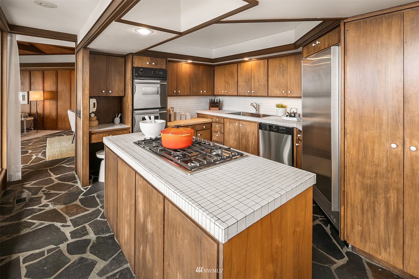 Kitchen with warm wood cabinets, white tile counters, a gas cooktop island, and stainless steel appliances.