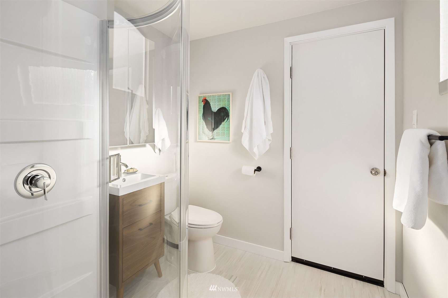Bathroom with a glass shower, wood vanity, and framed rooster artwork.