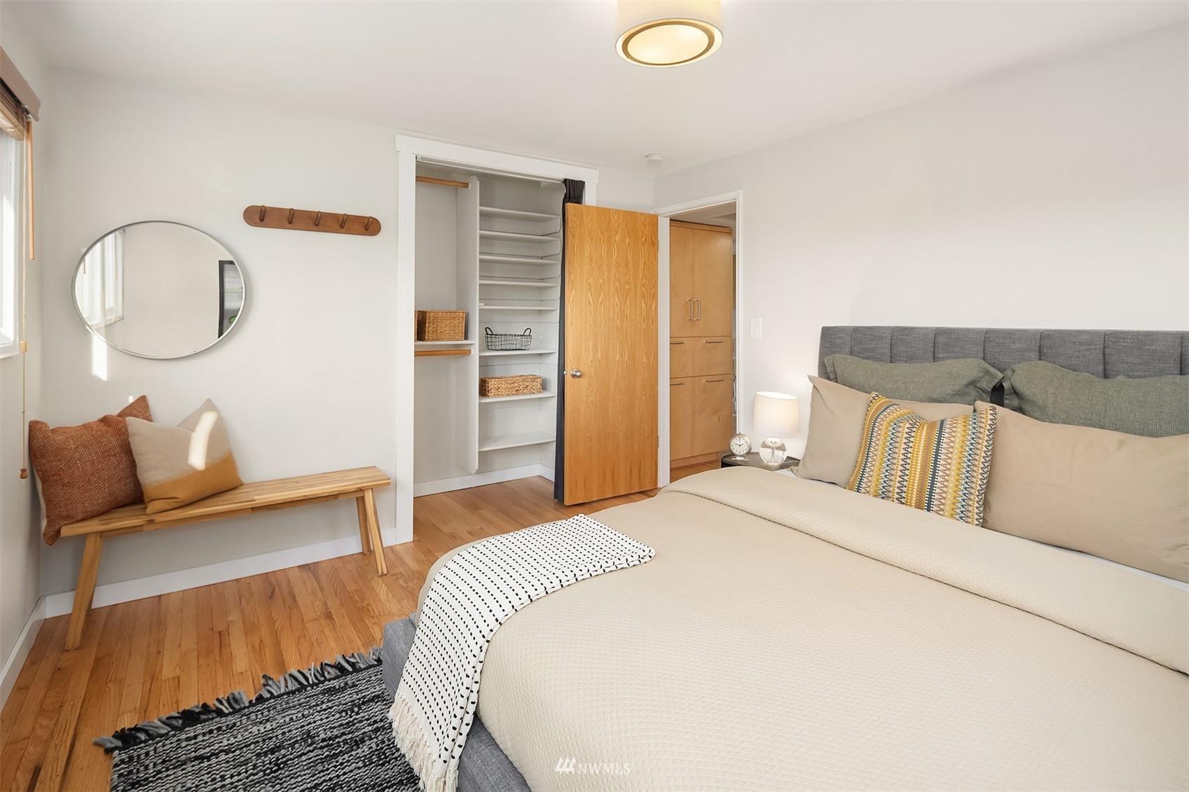 Staged bedroom with a large bed, hardwood floors, and an open closet with built-in shelves.