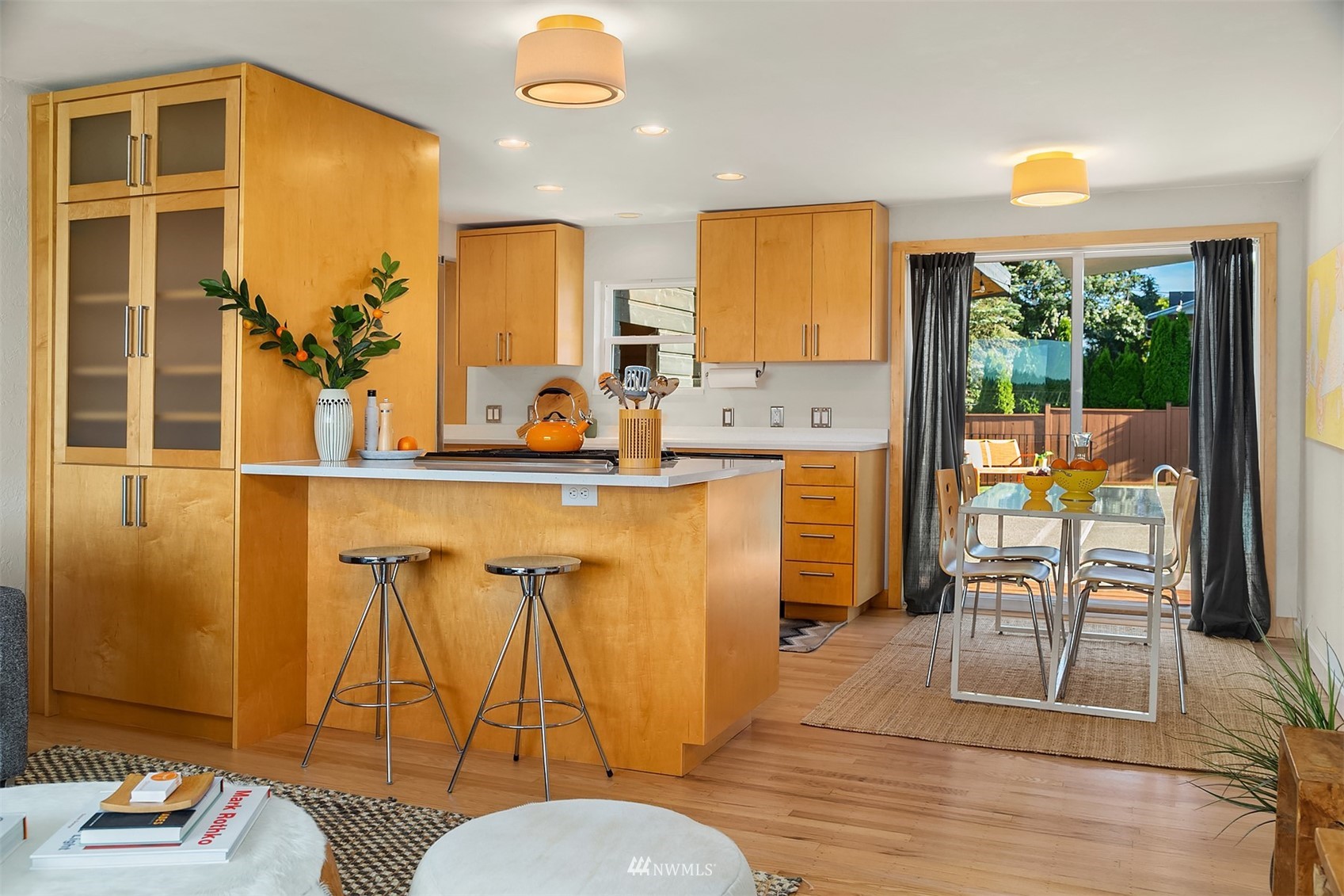 Kitchen with honey-colored wood cabinets, a breakfast peninsula, and dining area beside sliding glass doors.