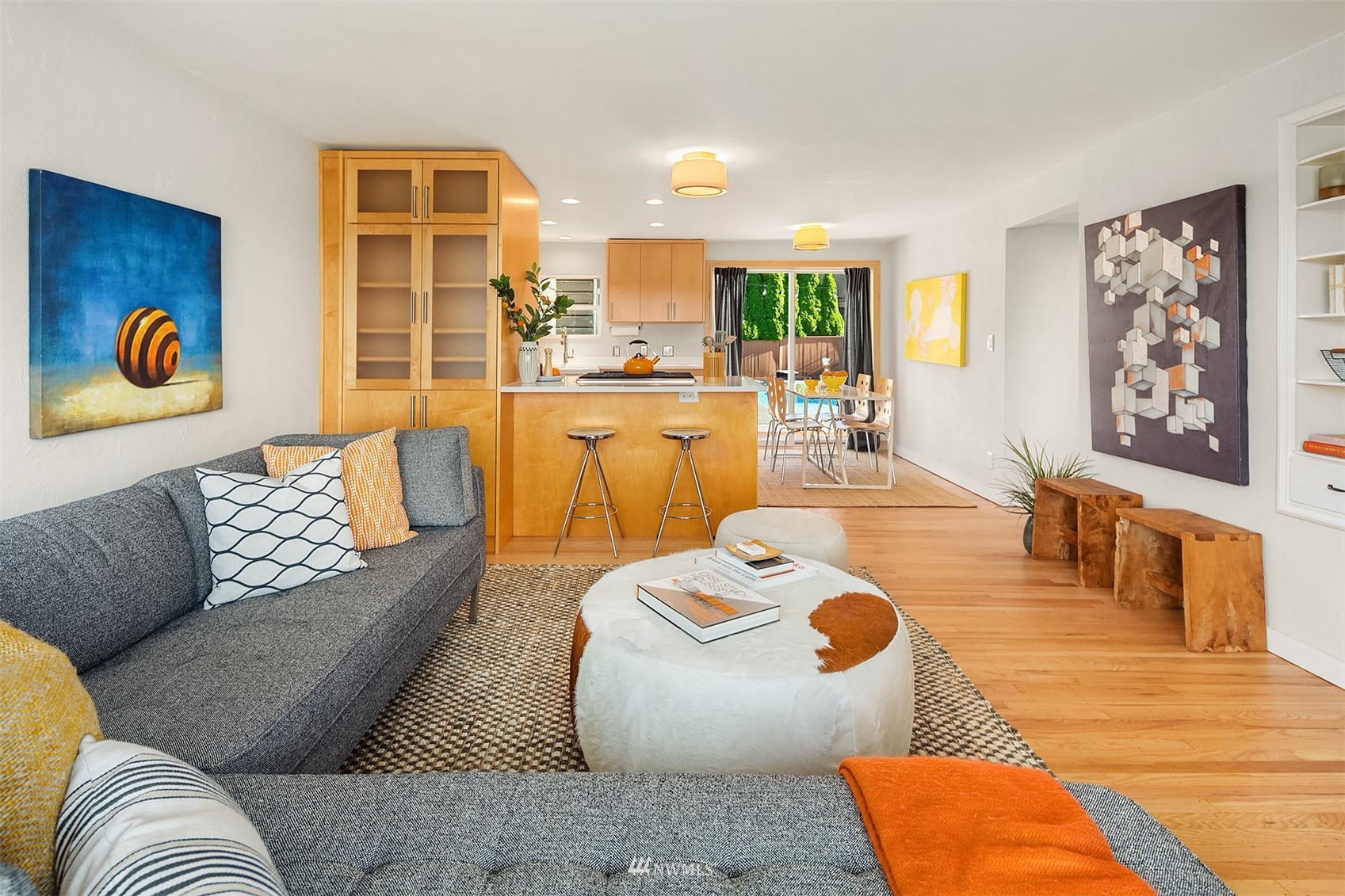Open-plan living room with gray sofas, a round coffee table, and a maple kitchen with breakfast bar.