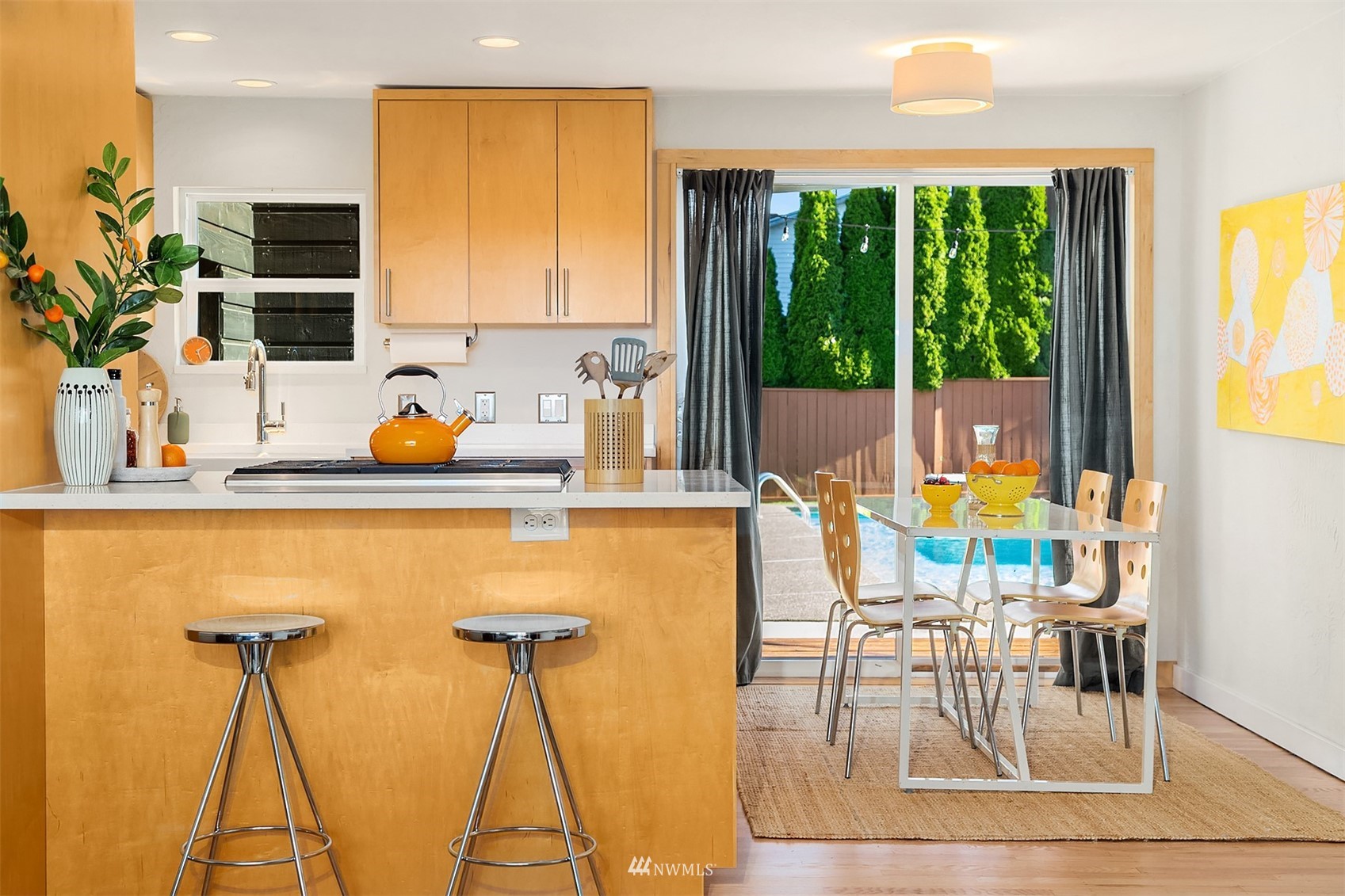 Kitchen with a wood breakfast bar and dining area overlooking a backyard swimming pool.