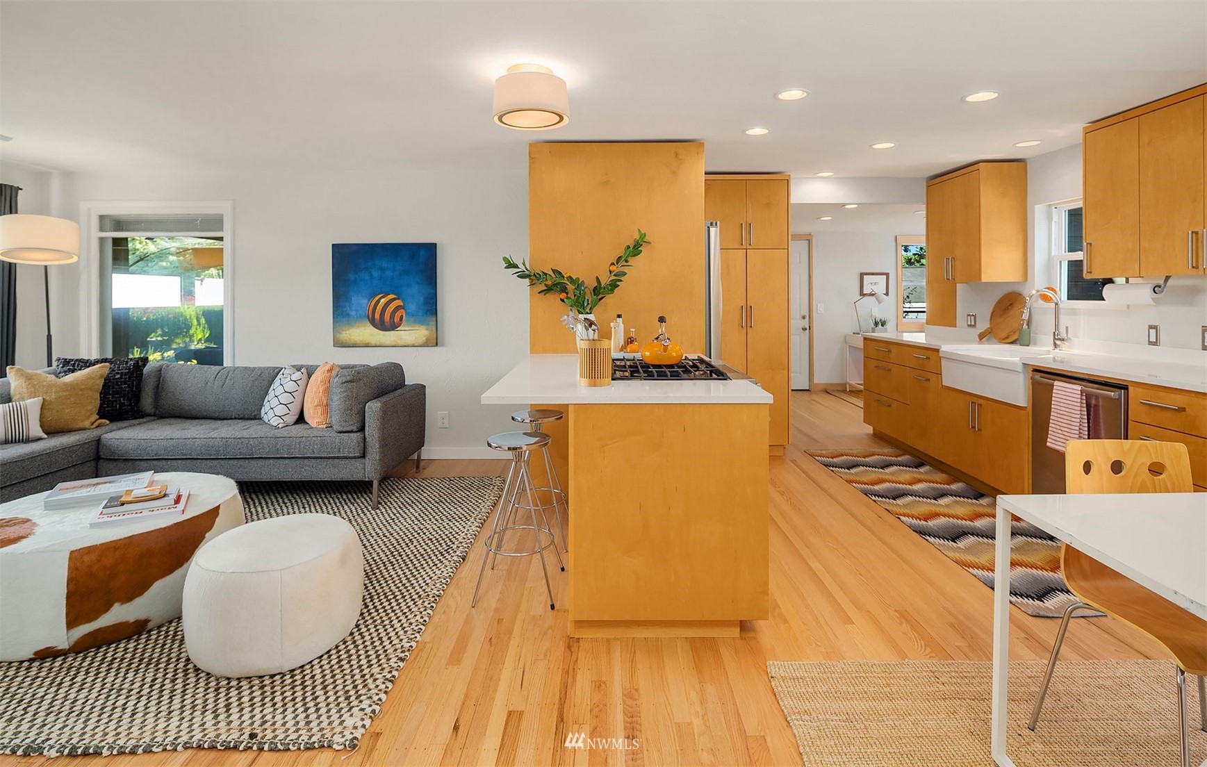 Open kitchen and living area with maple cabinetry, central island, and hardwood floors.