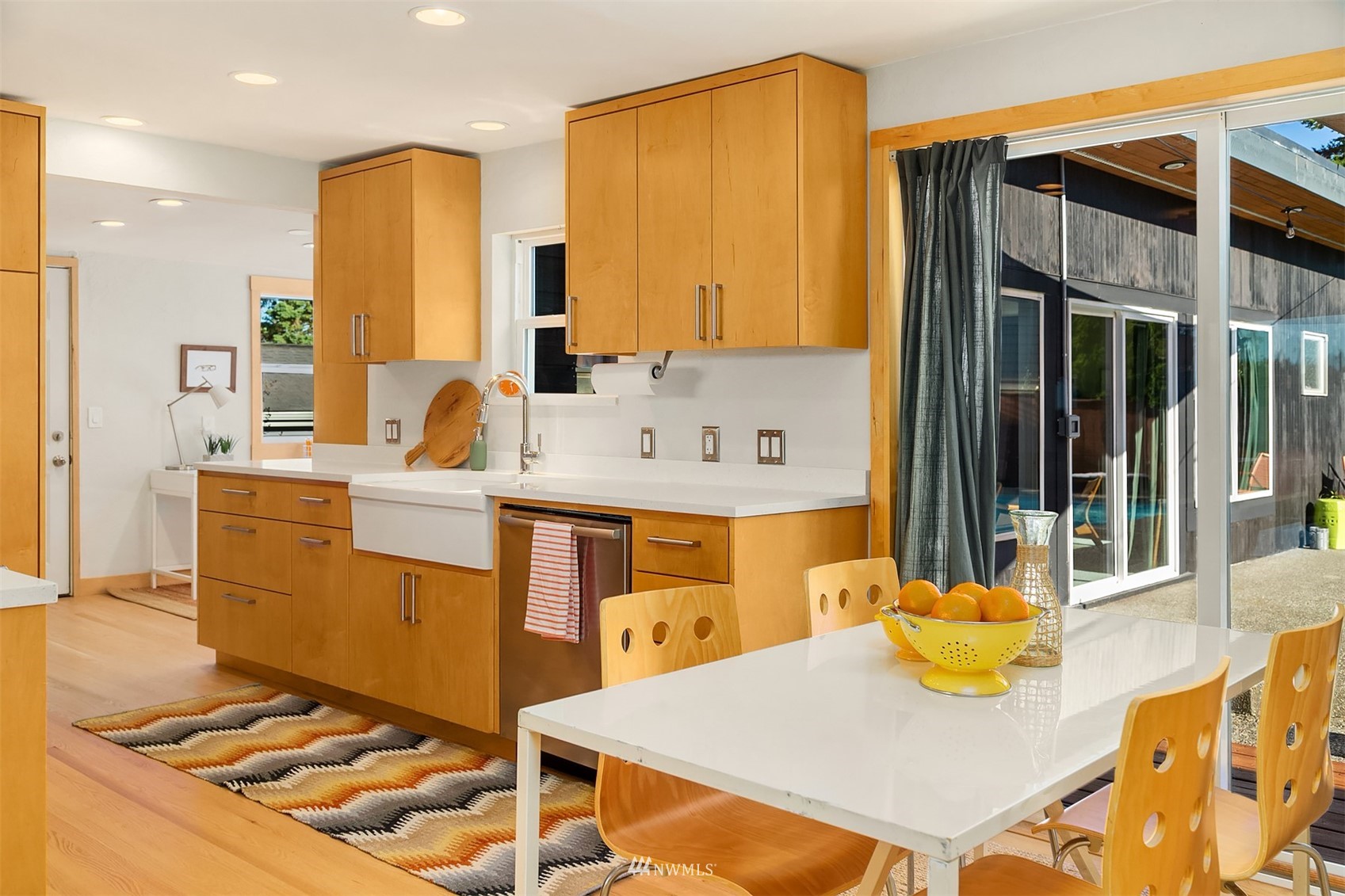 Open kitchen and dining area with wood cabinets, white countertops, and sliding doors to a patio.
