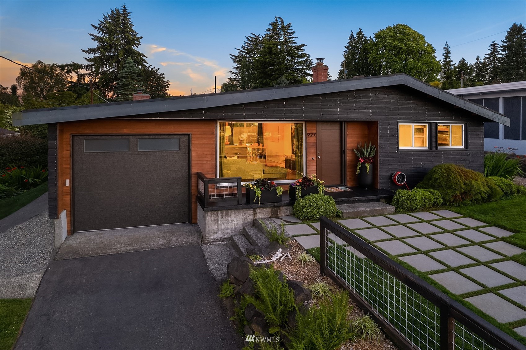Modern single-story Seattle home with dark siding, wood cladding, and a landscaped paver path.