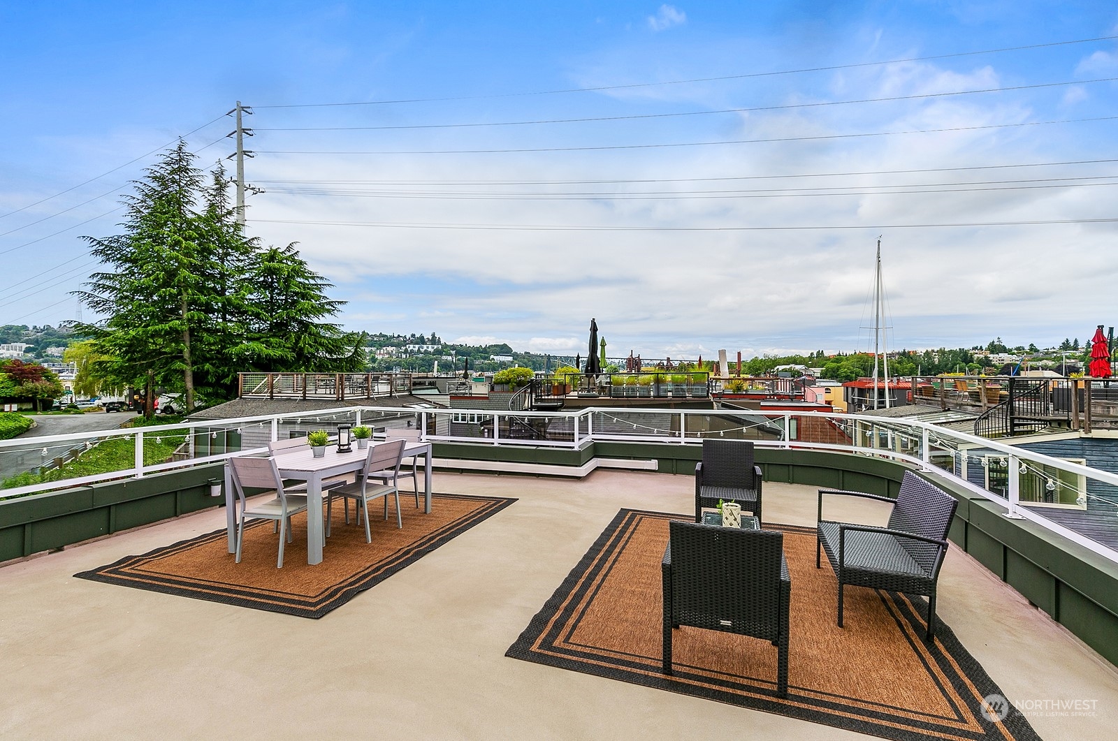 Rooftop deck with dining and lounge seating overlooking water and a tree-lined hillside.