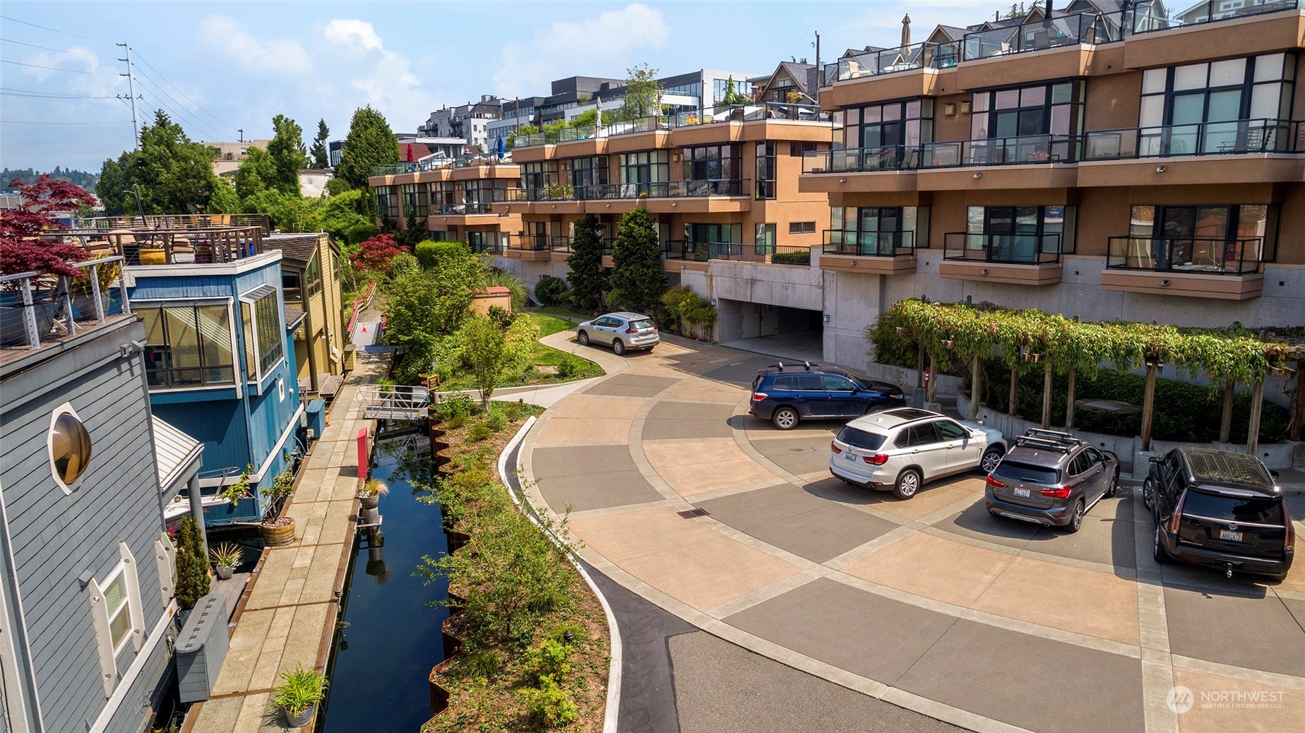 Condominium complex with glass balconies, courtyard parking, and a narrow canal alongside.