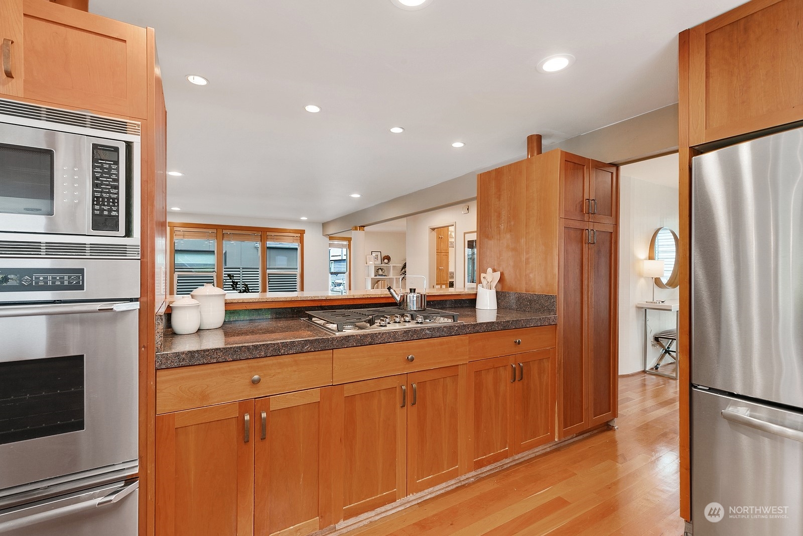 Kitchen with warm wood cabinets, dark stone counters, a gas cooktop, and stainless steel appliances.