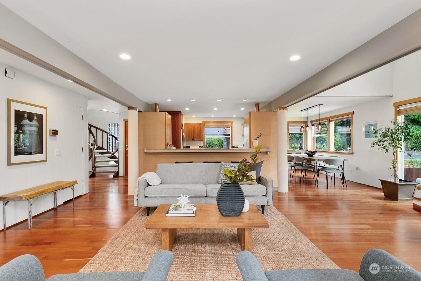 Open-plan living room with hardwood floors, gray sofa, and kitchen and dining area beyond.
