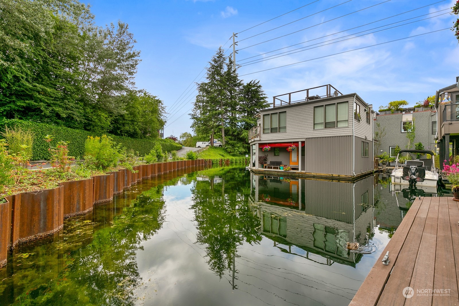 Waterfront home beside a calm canal, with a rooftop deck, dock, and moored boat.