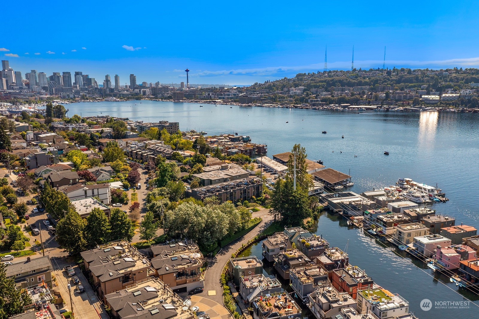 Aerial view of Lake Union, Seattle, with waterfront homes, marinas, downtown skyline, and the Space Needle.