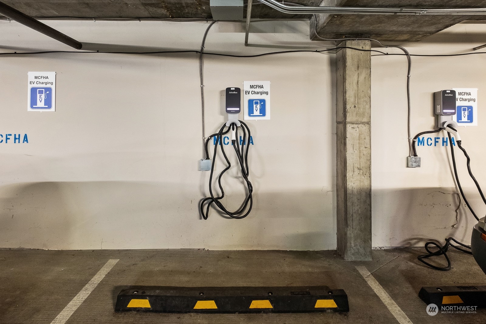 Garage parking area with two electric vehicle charging stations and marked parking spaces.