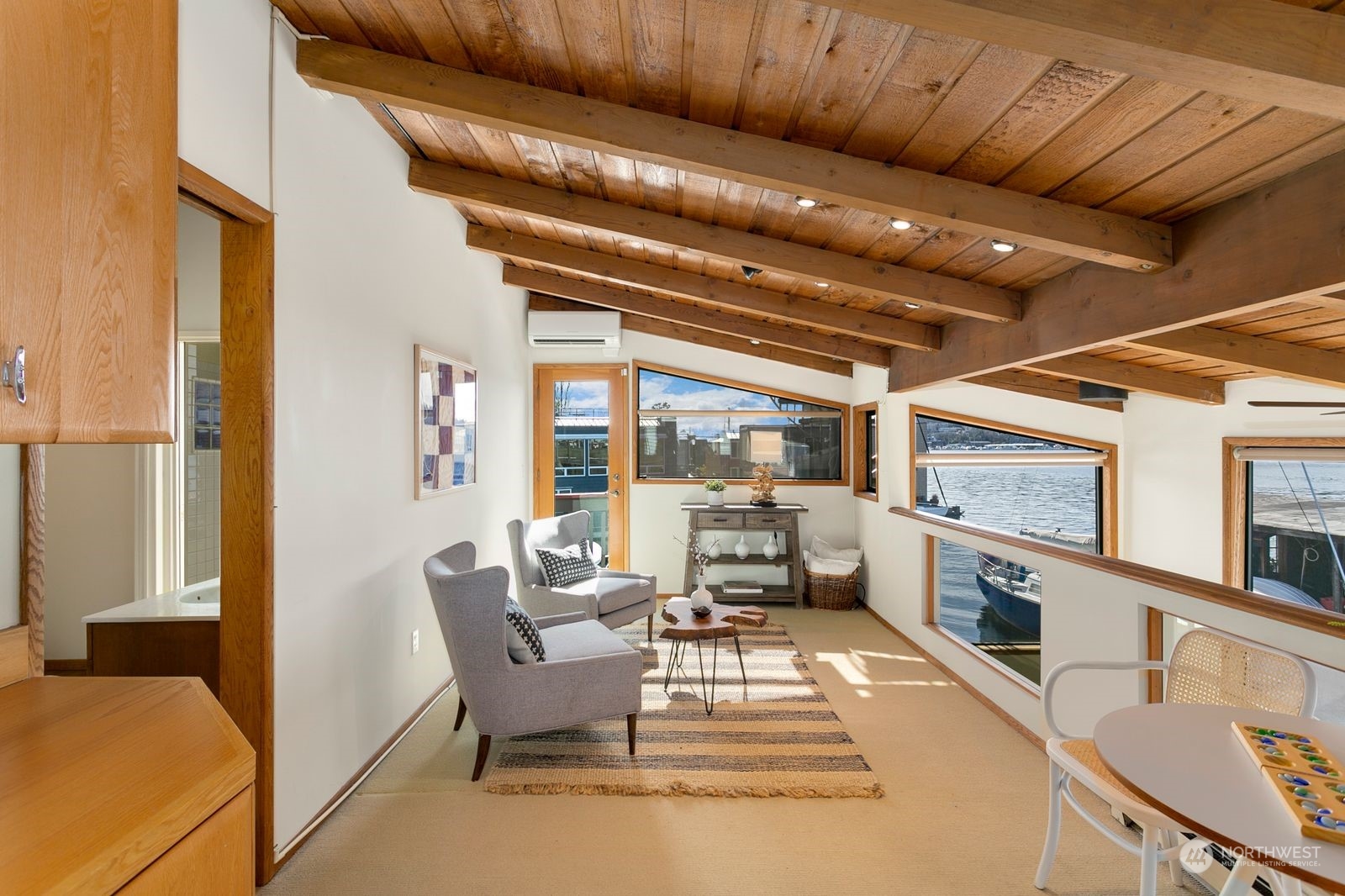 Living room with a vaulted wood ceiling and wide waterfront windows.