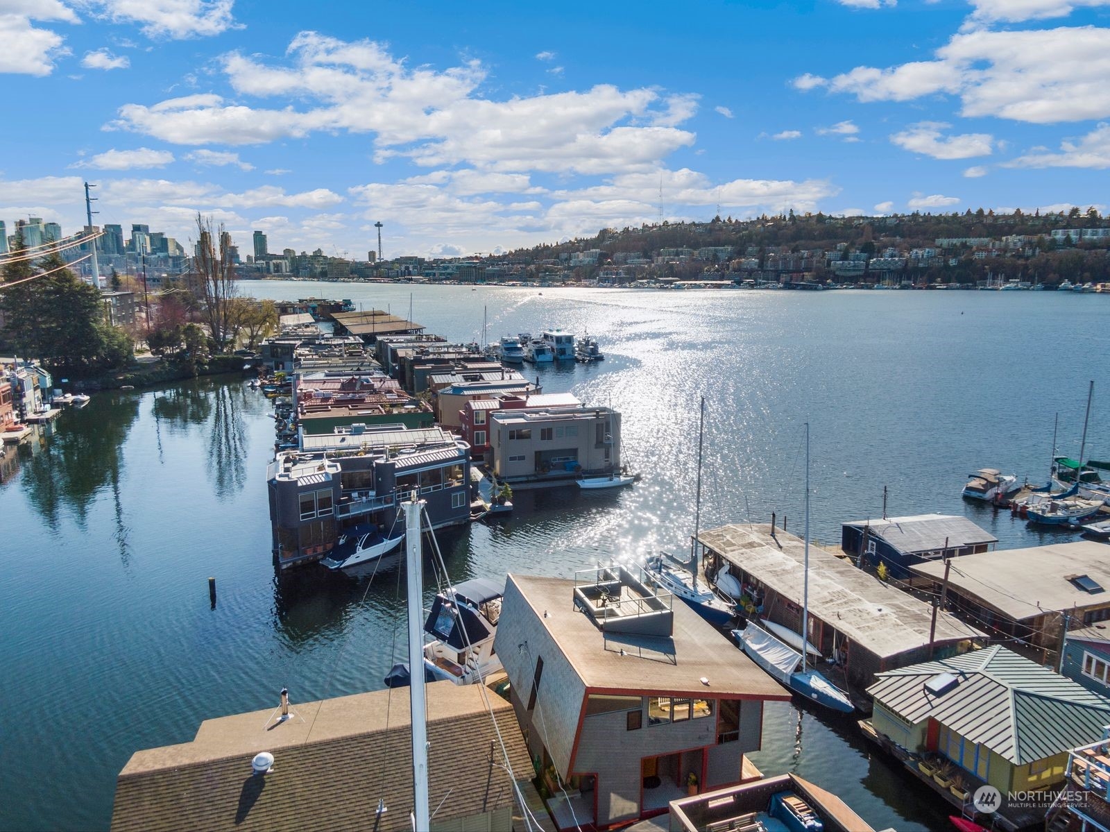 Aerial view of Lake Union floating homes, moored boats, and the Seattle skyline.