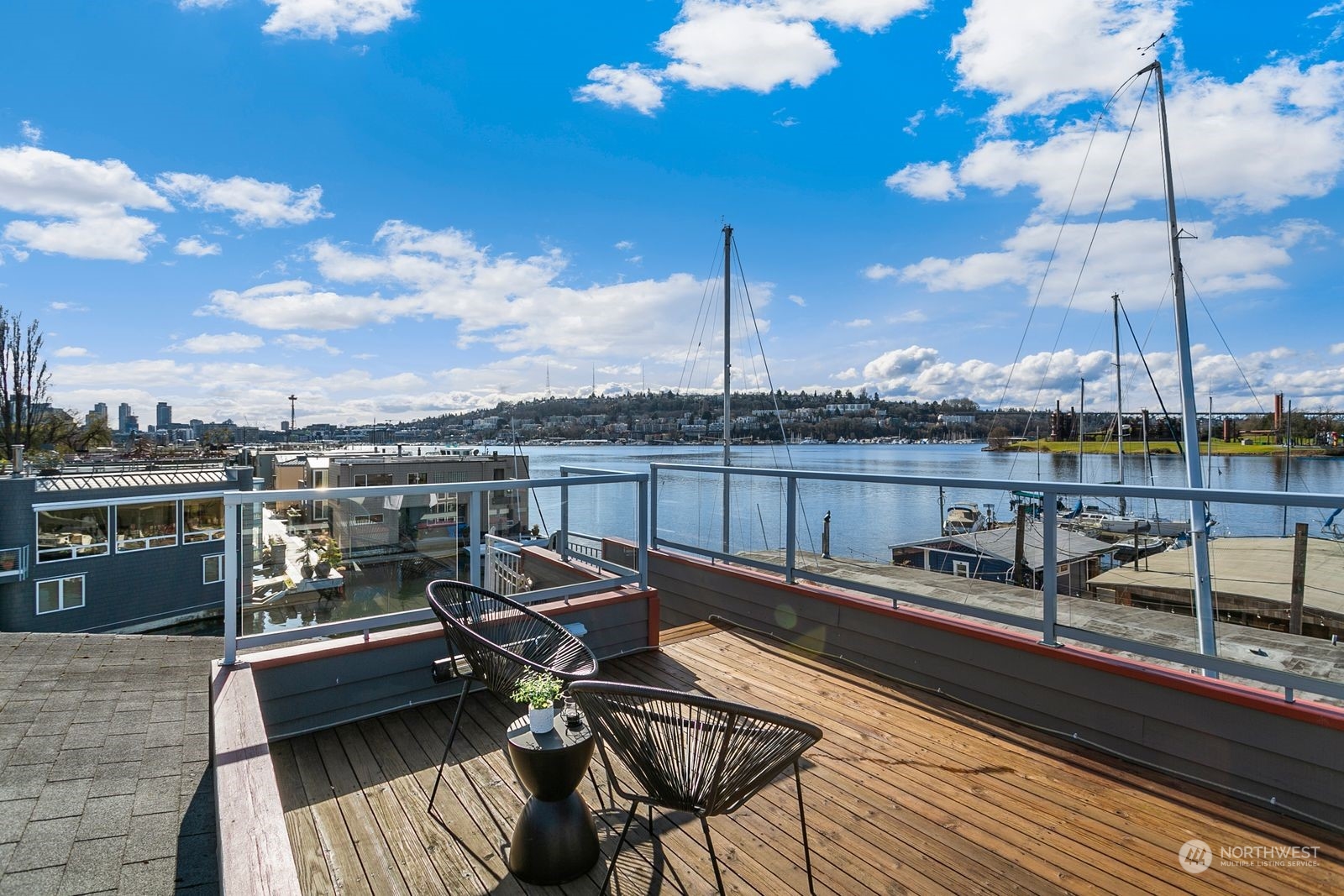 Rooftop deck overlooking Lake Union marina, with modern chairs and Seattle skyline in the distance.