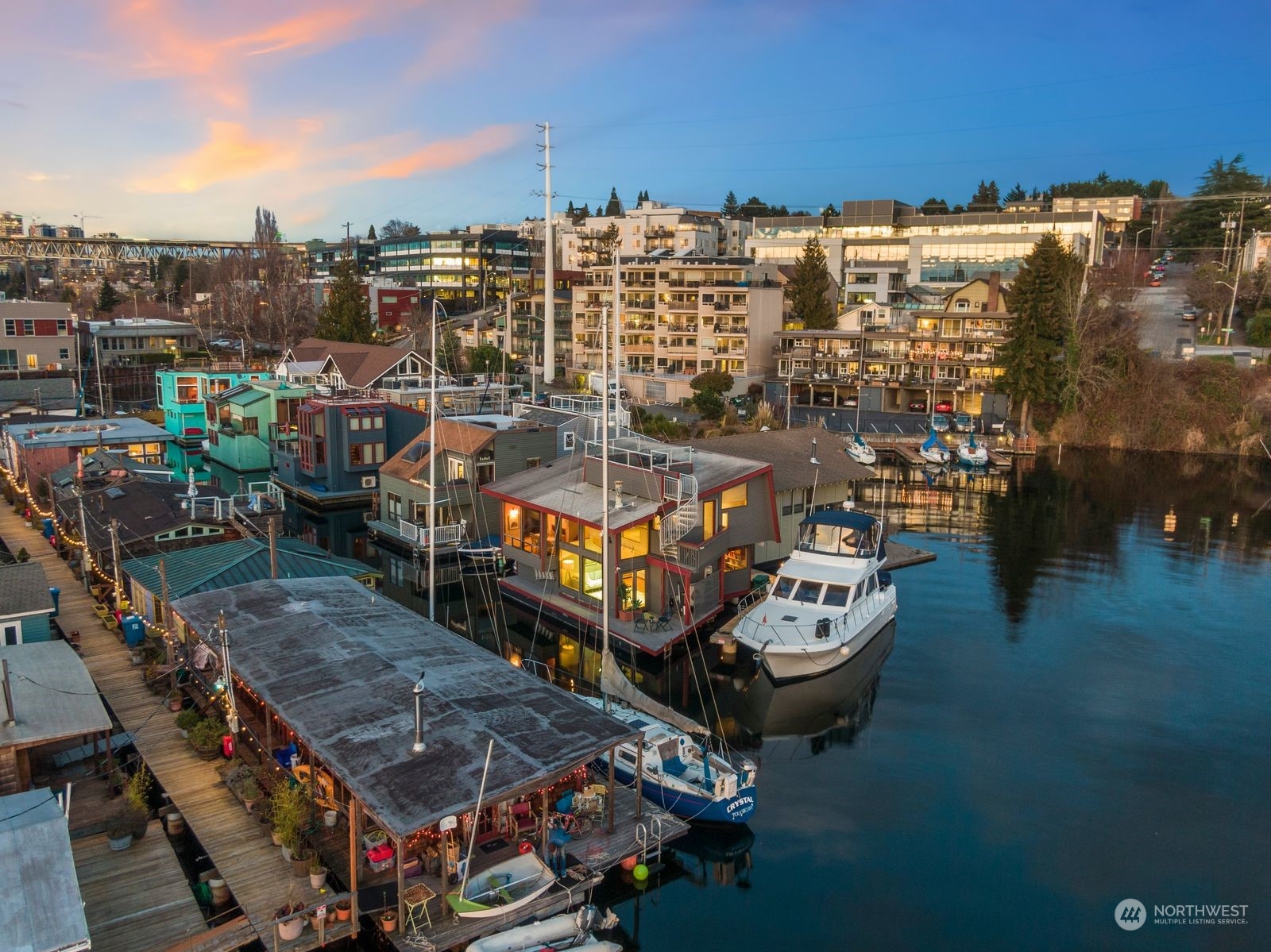Waterfront marina with floating homes and boats moored along the docks at sunset.